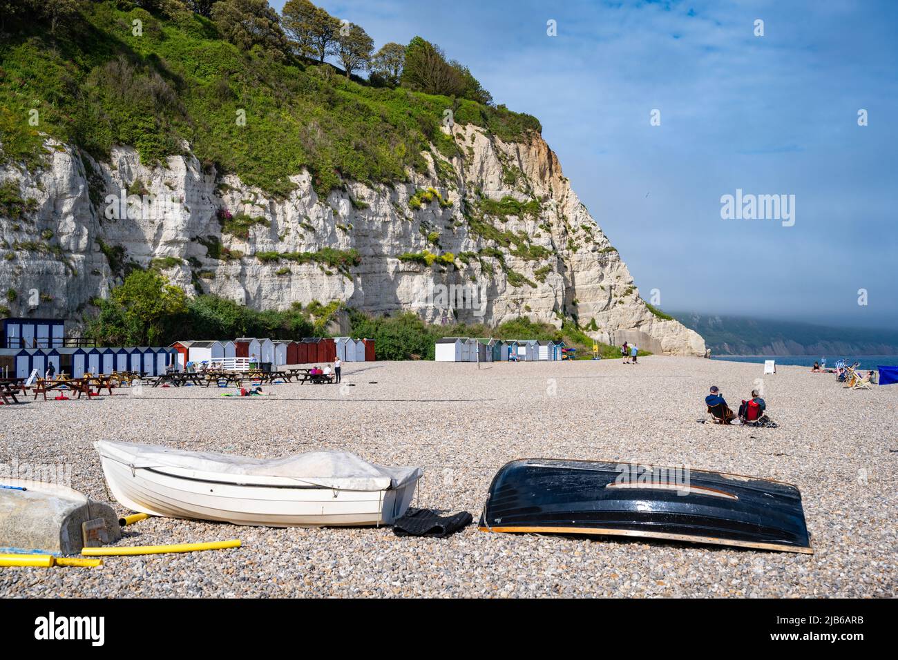 Barche sulla spiaggia di ciottoli e scogliere calcaree a Beer, Devon, Regno Unito Foto Stock