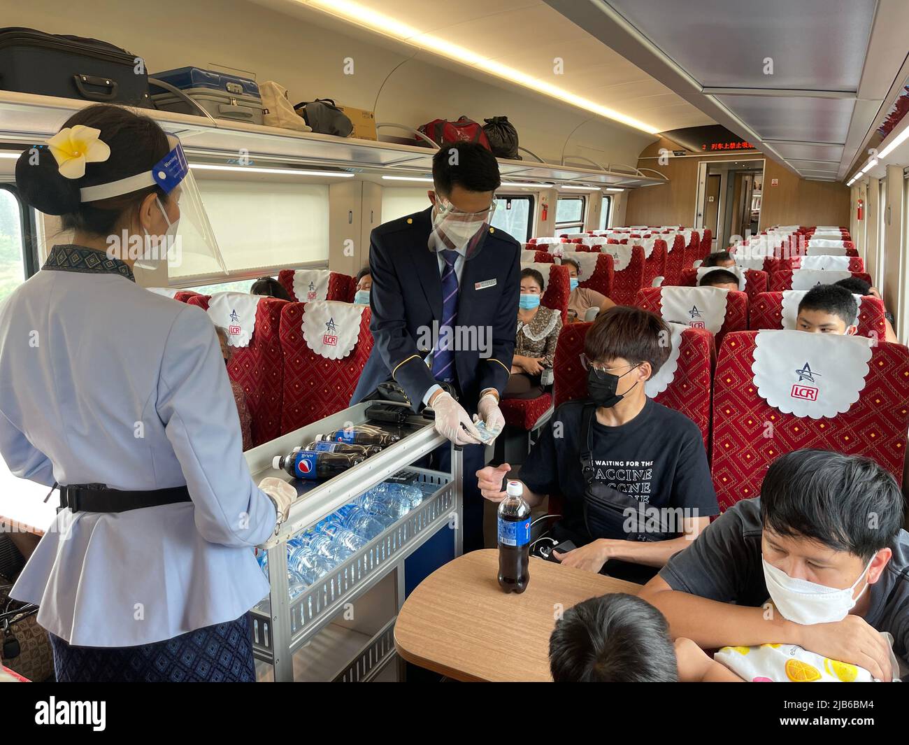 Vientiane. 25th maggio 2022. Gli stewards della Laos-China Railway Co., Ltd. (LCRC) servono passeggeri su un treno Lane Xang EMU il 25 maggio 2022. La ferrovia Cina-Laos, con un semestre di attività, ha consegnato oltre 4 milioni di tonnellate di merci a partire da giovedì, ha affermato l'operatore ferroviario cinese. Come progetto di riferimento nell'ambito dell'iniziativa Belt and Road, la ferrovia di 1.035 km collega la Kunming cinese con la capitale laotiana Vientiane. Credit: Han Jialing/Xinhua/Alamy Live News Foto Stock