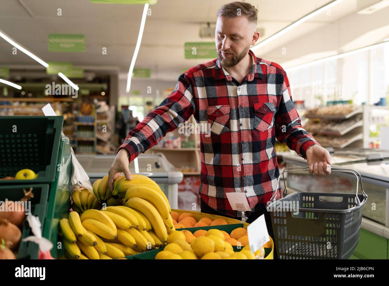 L'uomo sceglie la frutta nel supermercato. L'uomo acquista banane e verdure biologiche. Il ragazzo sceglie le merci dalla drogheria della mensola Foto Stock