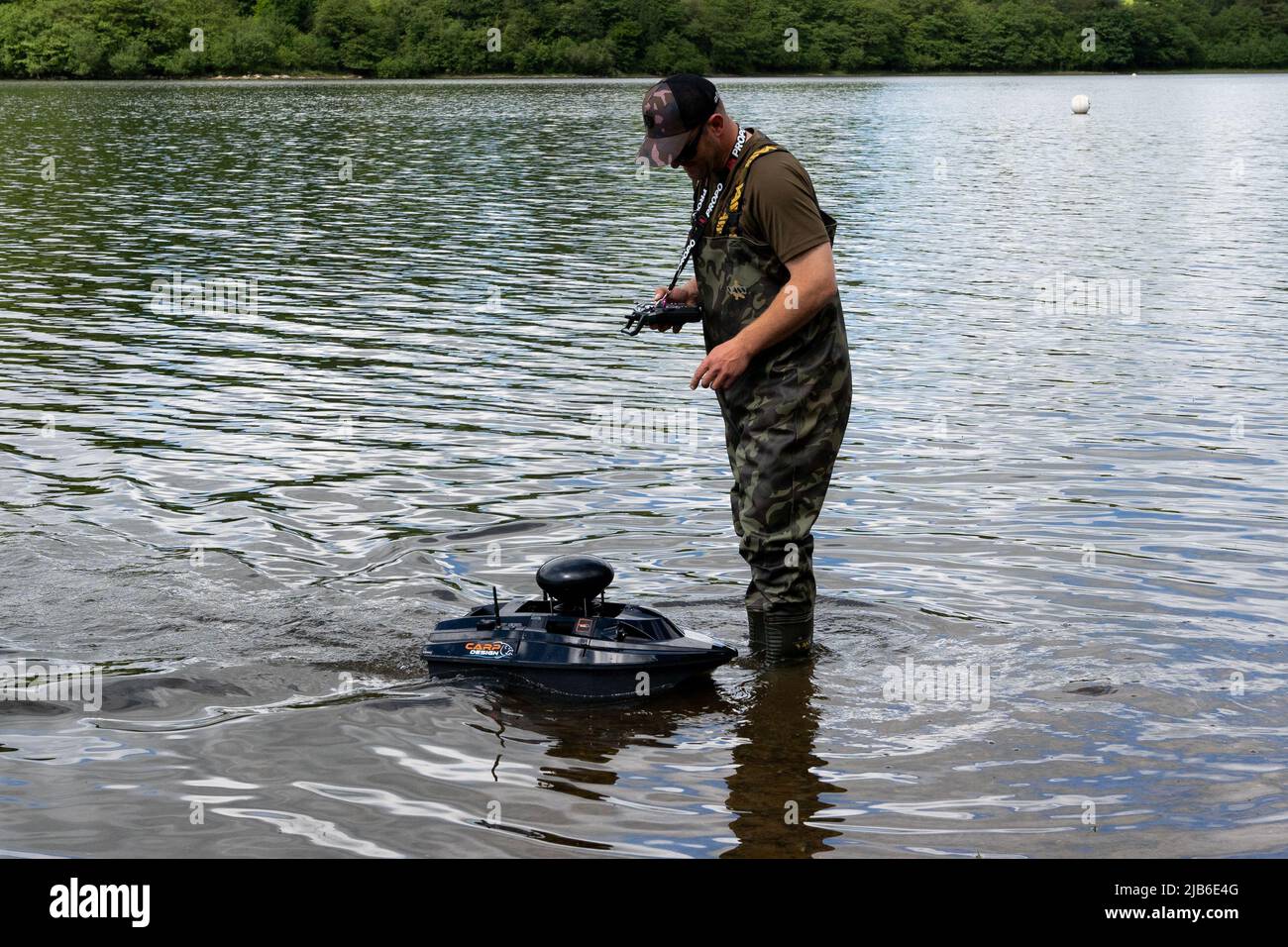 Angler gestisce una barca con esca a controllo remoto sul lago nella campagna dello Staffordshire Foto Stock