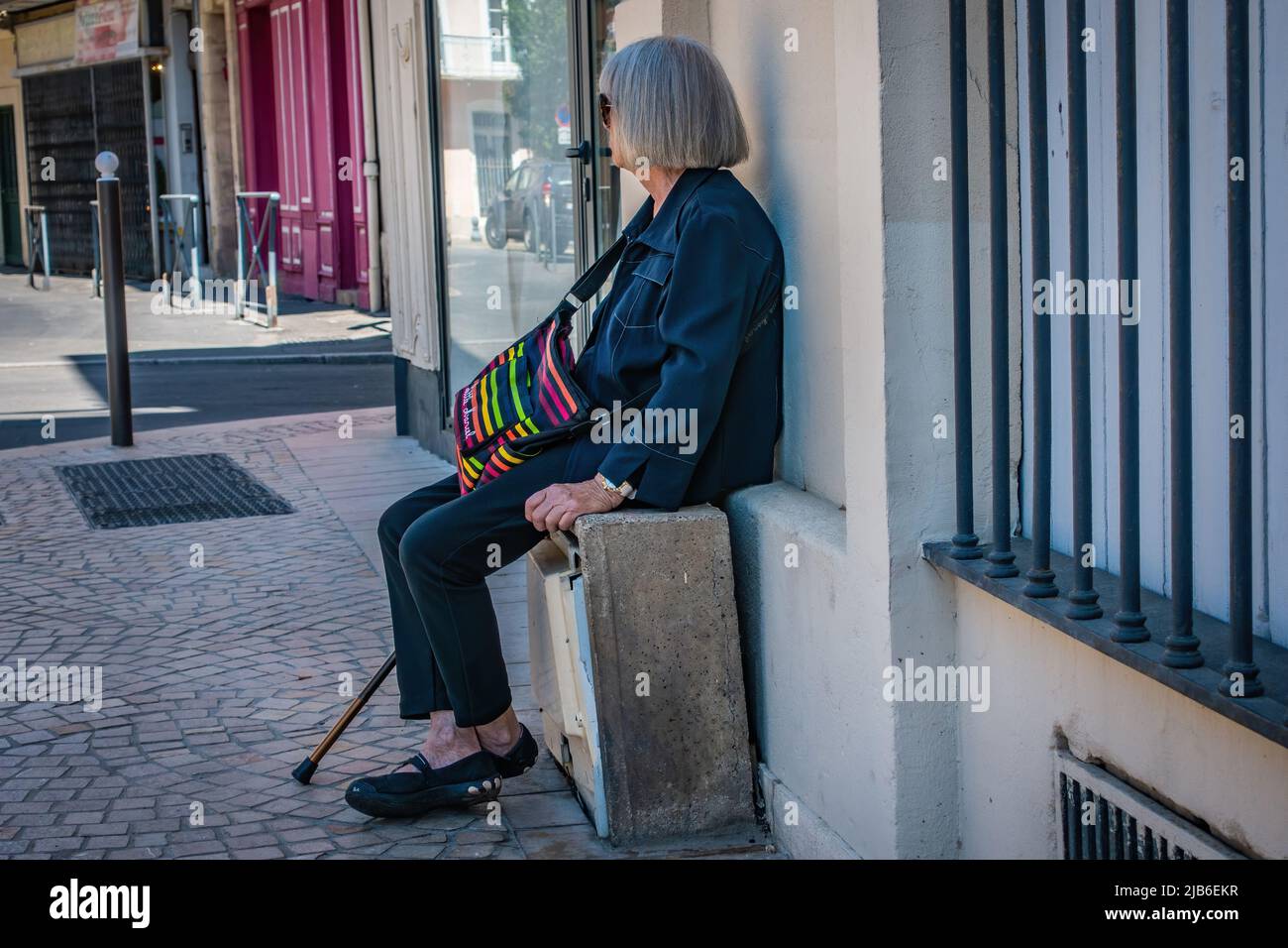 Signora anziana che prende una pausa dal camminare a Beziers, Francia. Foto Stock