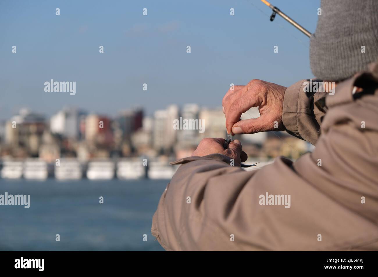 Il pescatore prende un pesce da un gancio da pesca con uno sfondo bokeh. Foto Stock