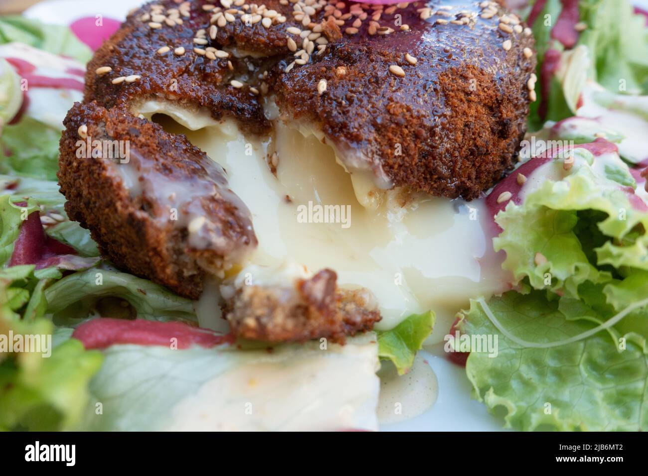 Cheeze di camembert fuso e cotto servito in Francia con un'insalata laterale Foto Stock