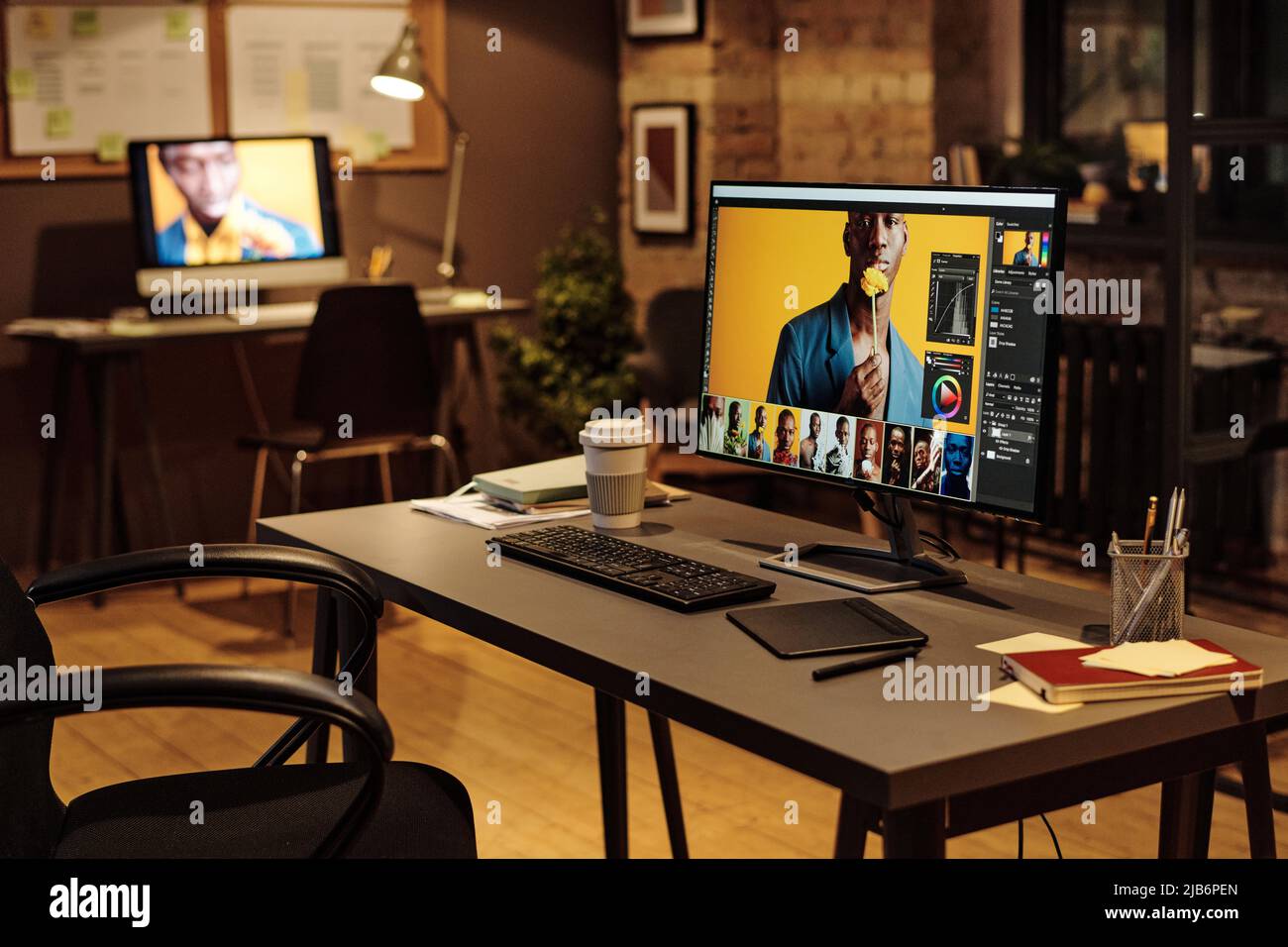 Immagine di tavolo con monitor per computer e tablet grafico per designer in ufficio moderno in serata Foto Stock