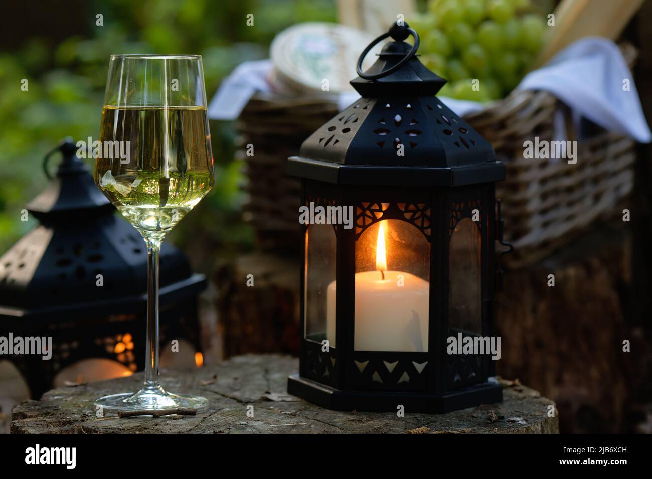 Vino in vetro cristallo con una candela in una lanterna all'interno del bosco, fotografia promozionale per la degustazione di vini all'aperto. Foto Stock