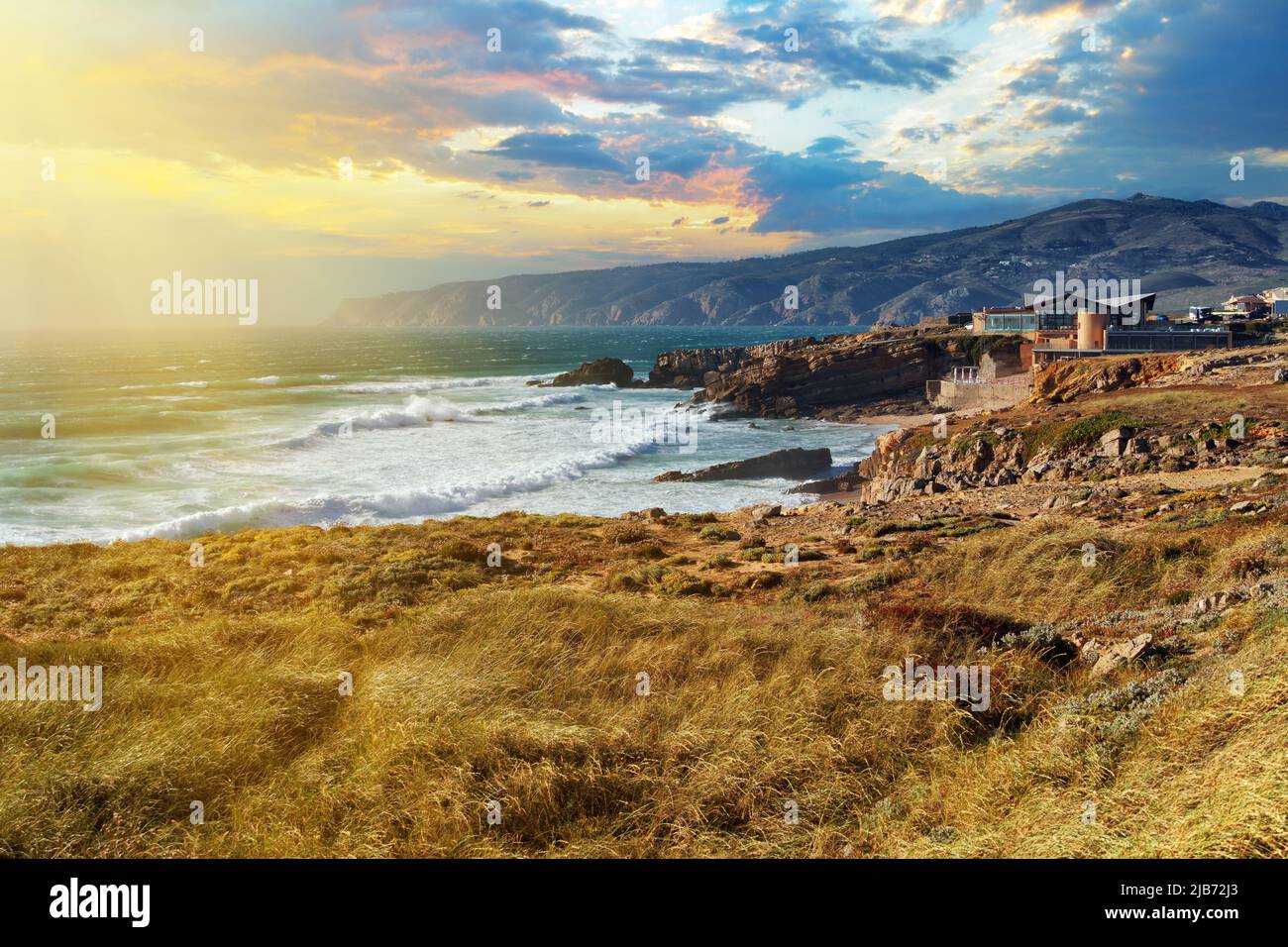 Vista panoramica della costa rocciosa dell'infuriante Oceano Atlantico vicino a Capo Roca alla luce del sole tramontato in Portogallo. Comune di Sintra, Lisbona Foto Stock