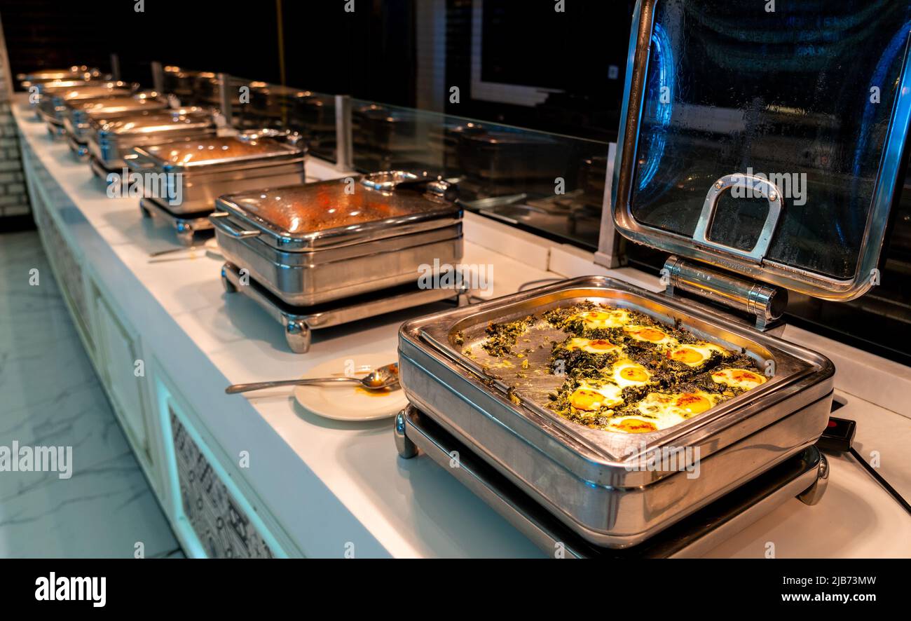 Buffet all-inclusive in vassoi riscaldanti nel ristorante dell'hotel con uova e spinaci per la prima colazione Foto Stock