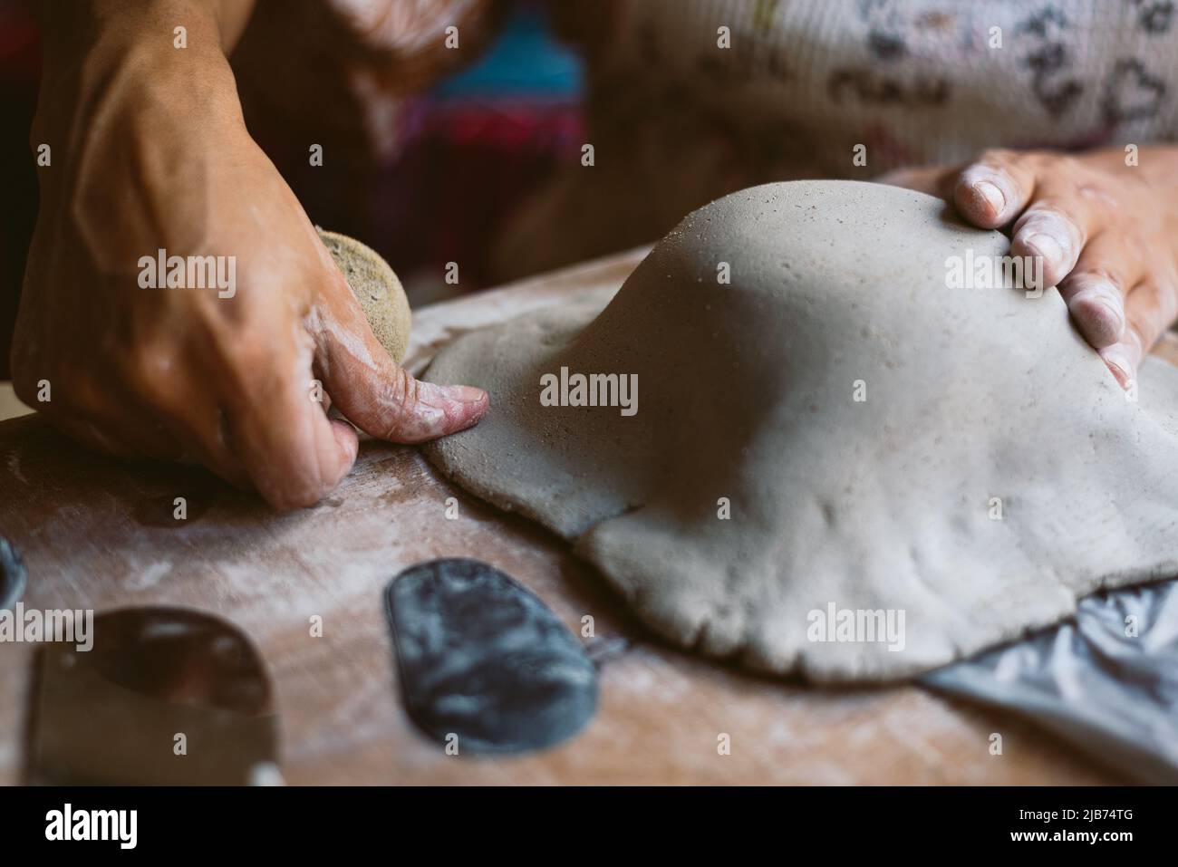 Primo piano delle mani donna che lavorano argilla facendo ceramica a casa. Concetto di hobby e creatività a casa. Impastare e inumidire l'argilla. Foto Stock