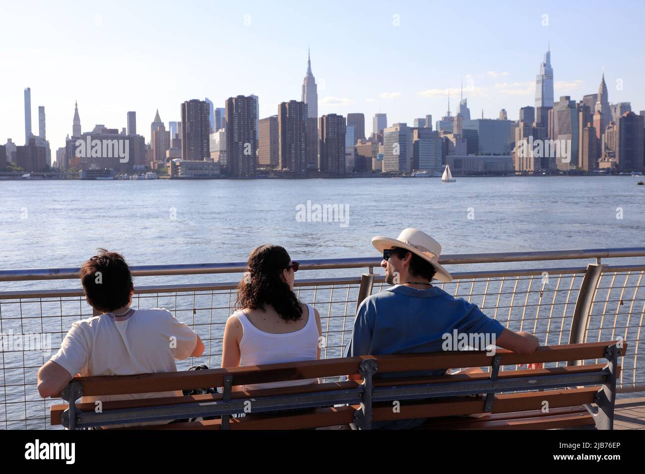 I visitatori si rilassano sul lungomare del WNYC Transmitter Park con l'East River e lo skyline di Manhattan sullo sfondo.Greenpoint.Brooklyn.New York City. Foto Stock