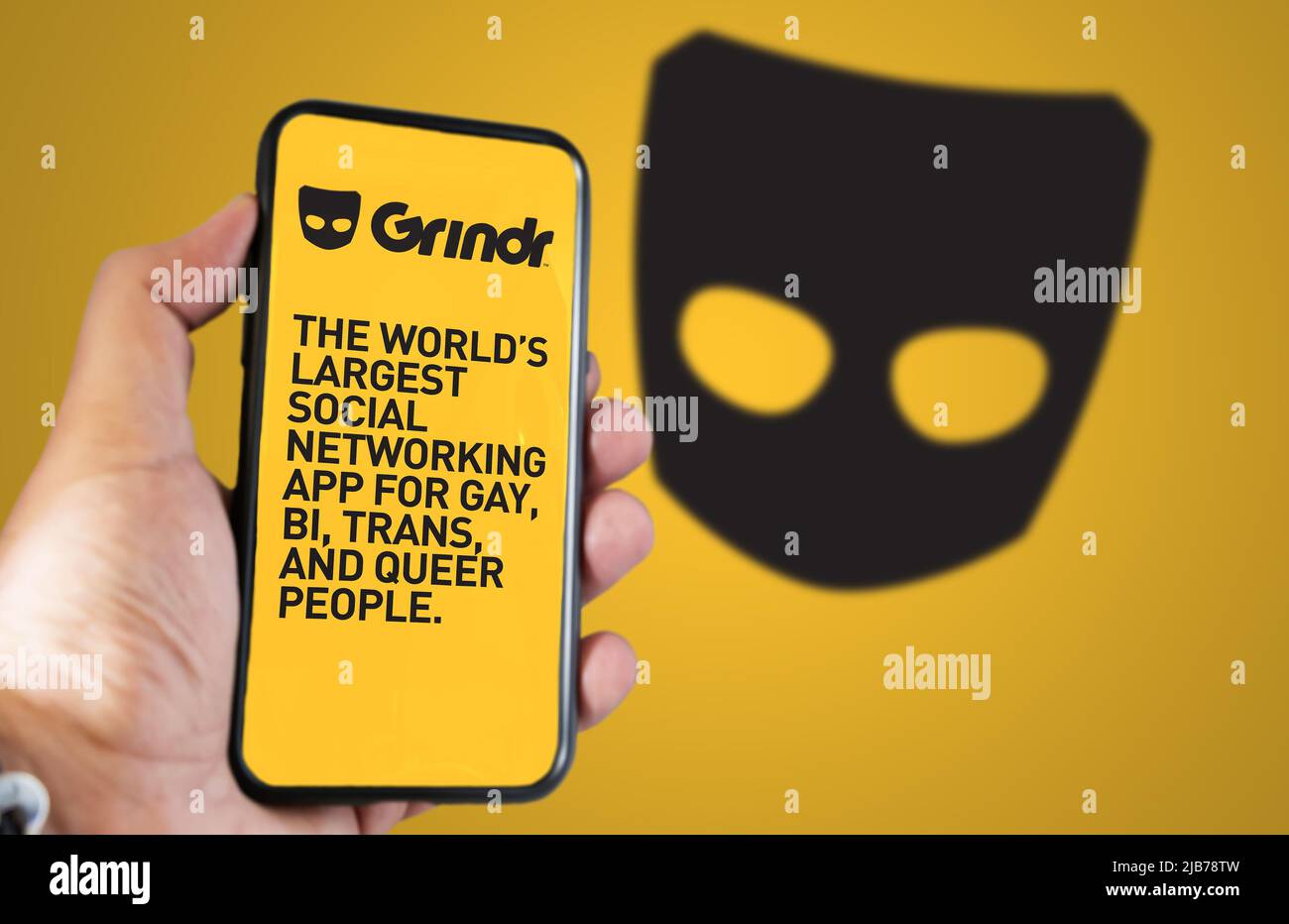 San Francisco, CA, USA, maggio 2022: Tenere a mano un telefono con l'applicazione mobile Grindr sullo schermo. Sullo sfondo il logo Grindr si offuscava. Grindr è datin Foto Stock