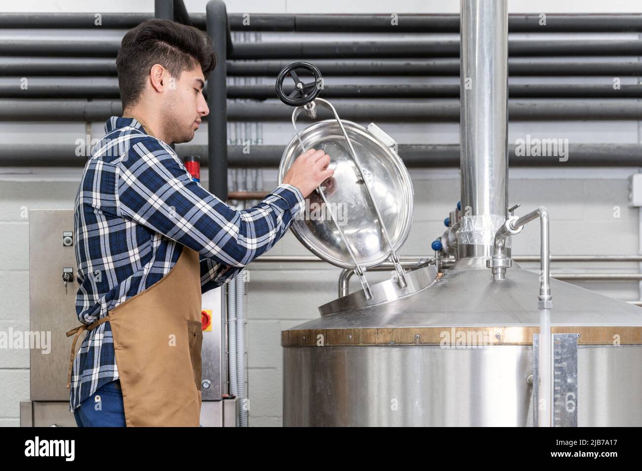 Vista ravvicinata di un birrificio artigianale che lavora presso una fabbrica di birra artigianale. Fotografia di alta qualità Foto Stock