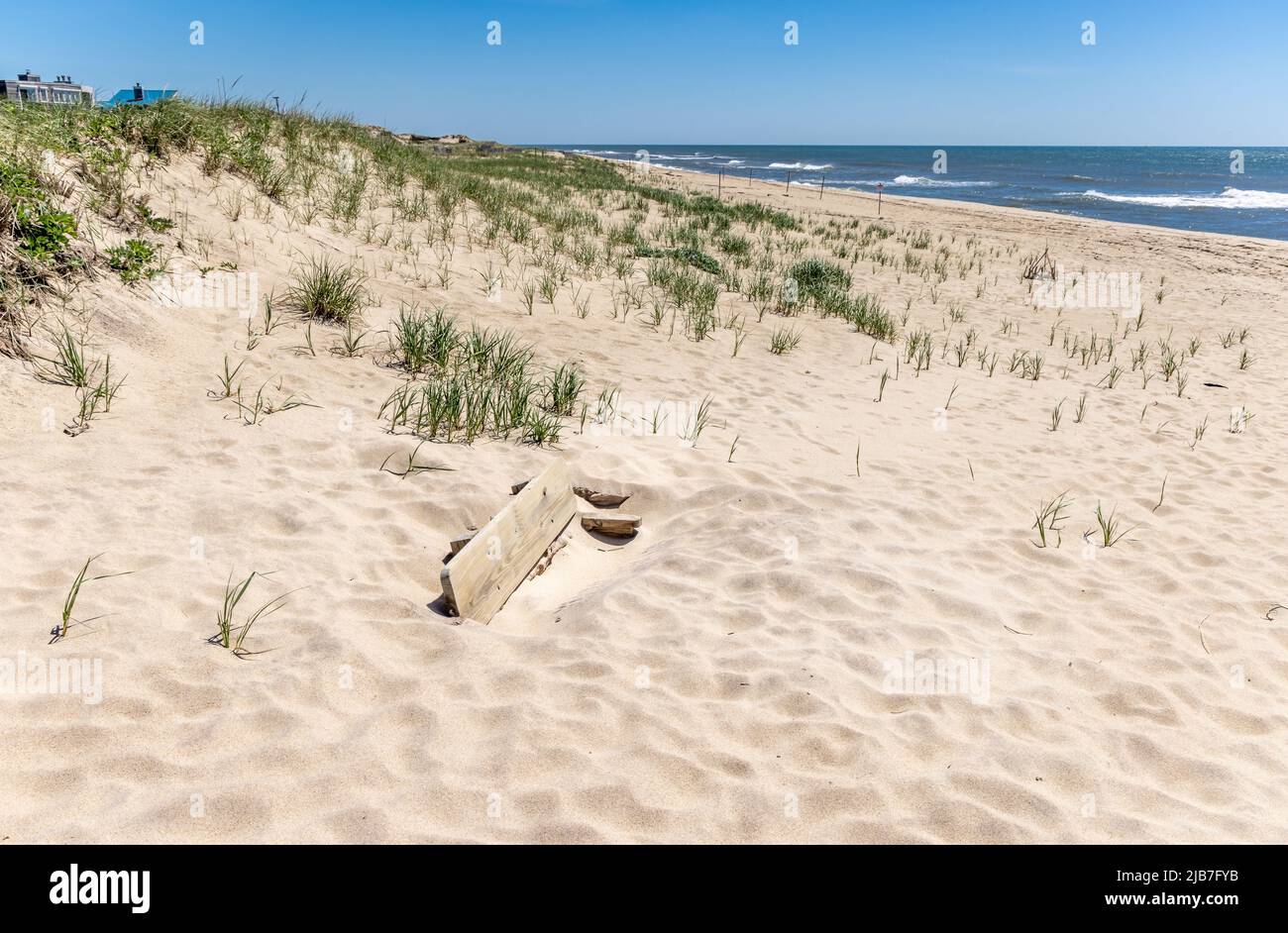 Panca di parco sepolto in sabbia ad una spiaggia di Amagansett Foto Stock