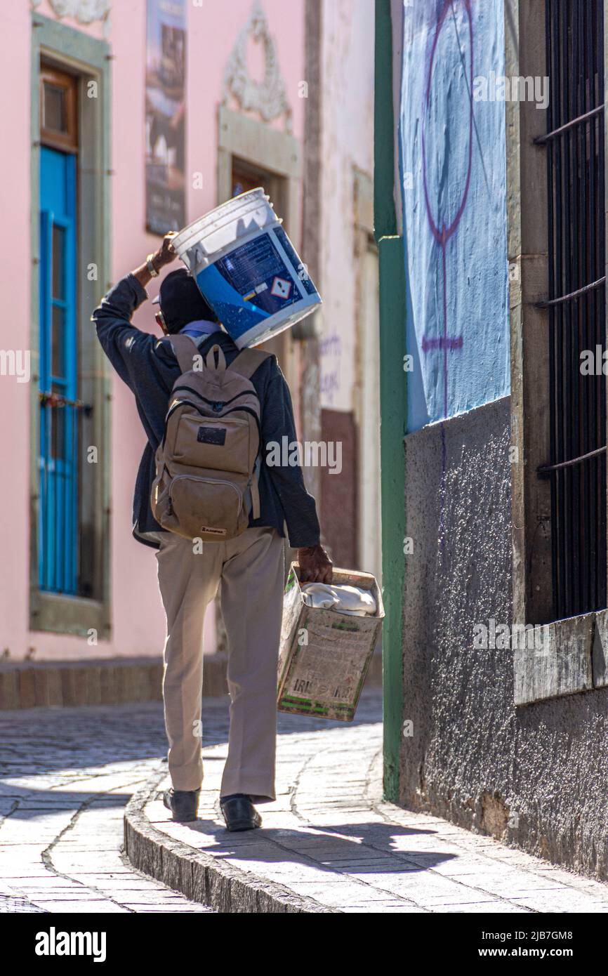 Un uomo che porta forniture di costruzione sulla sua mano destra e dovrebbe. San Miguel de Allende, Messico. Foto Stock