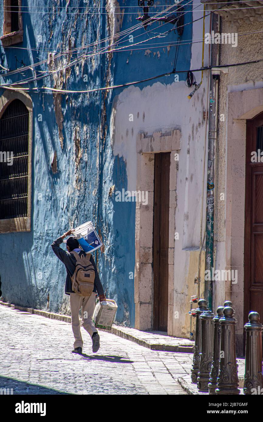 Un uomo che porta forniture di costruzione sulla sua mano destra e dovrebbe. San Miguel de Allende, Messico. Foto Stock