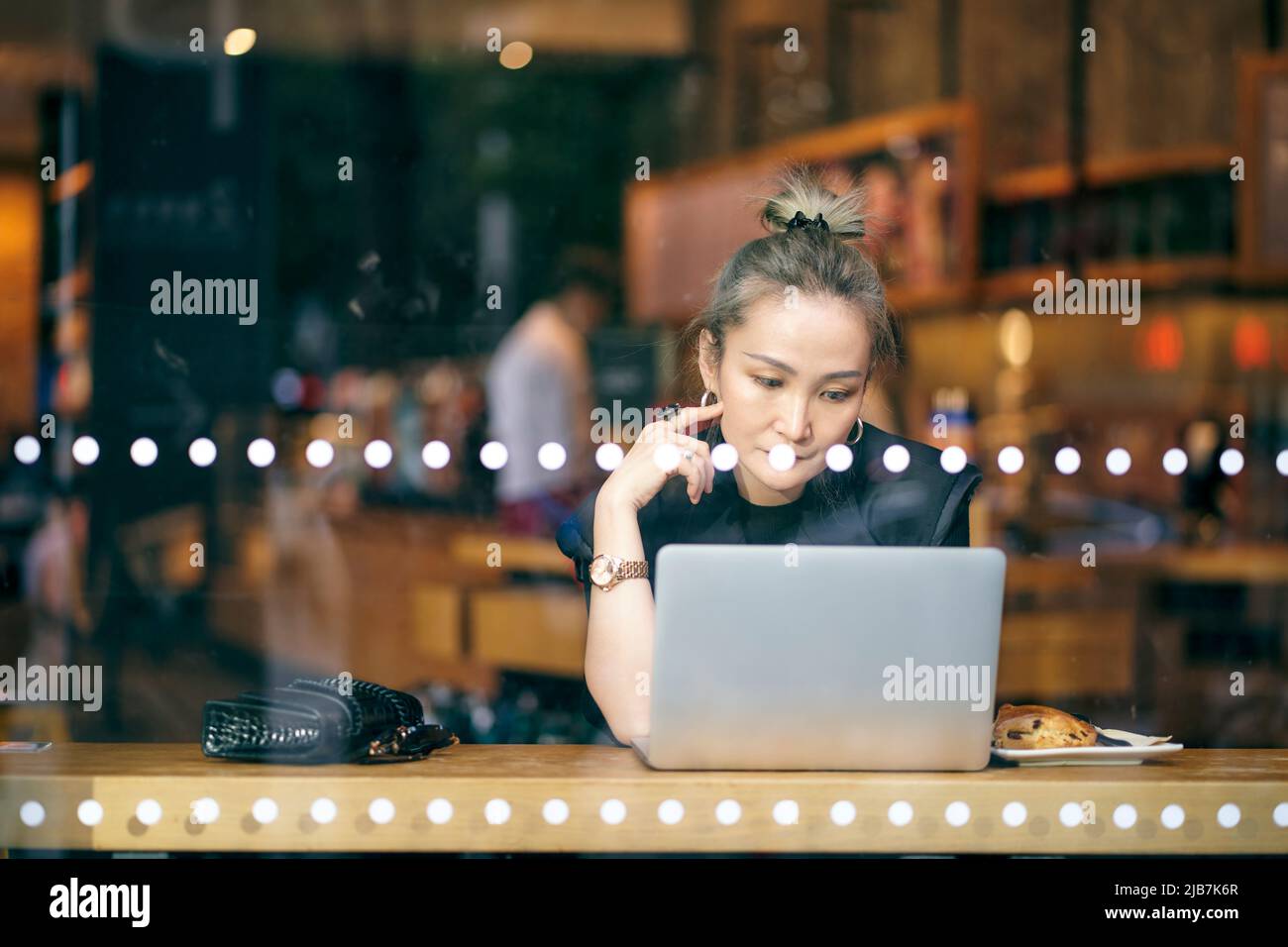 donna asiatica che lavora in caffetteria usando un computer portatile Foto Stock