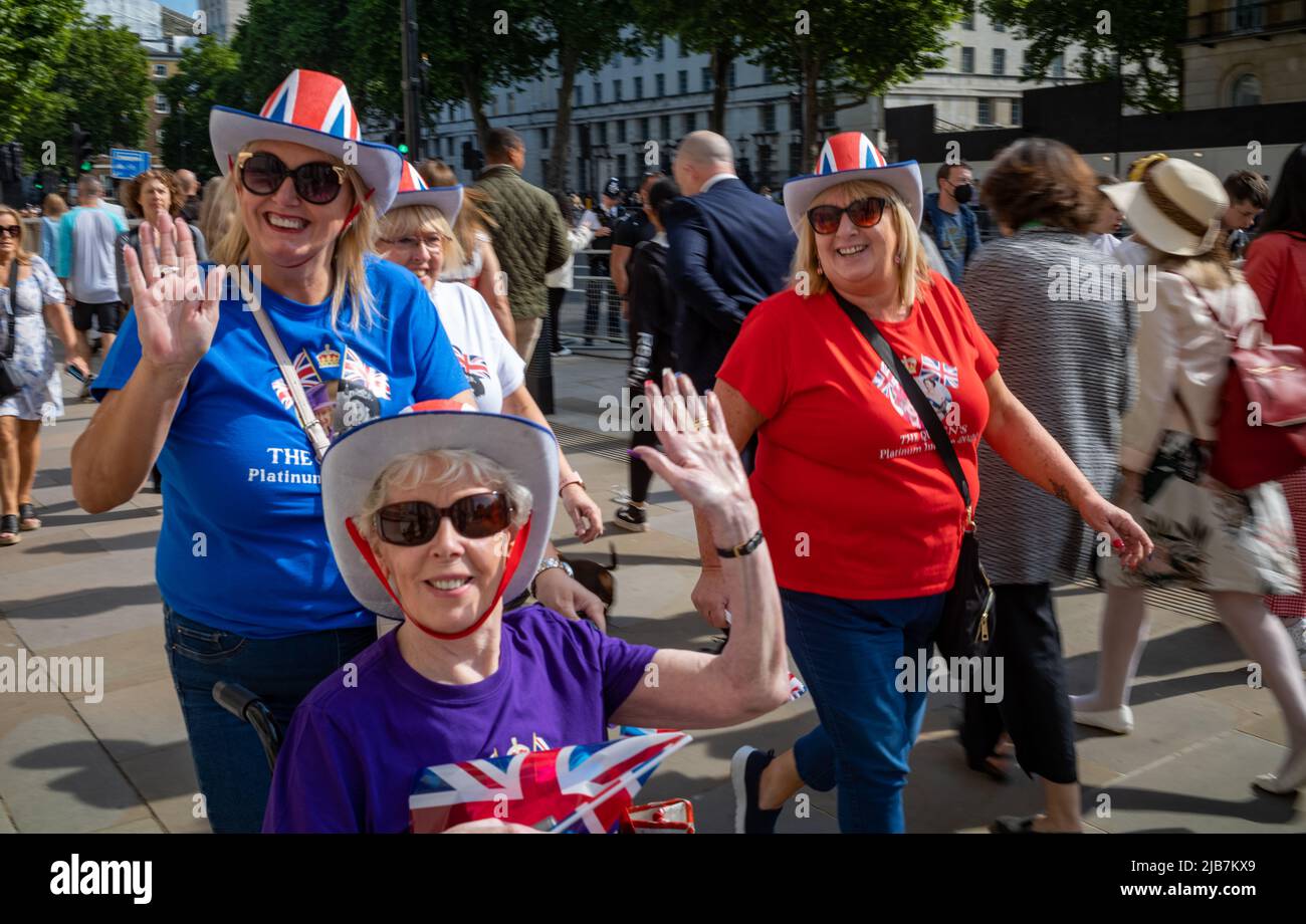 Tre donne royaliste vestite con bandiere unioine ondano mentre partecipano agli eventi per il giubileo di platino della regina a Londra. La regina Elisabetta segnava 70 yea Foto Stock