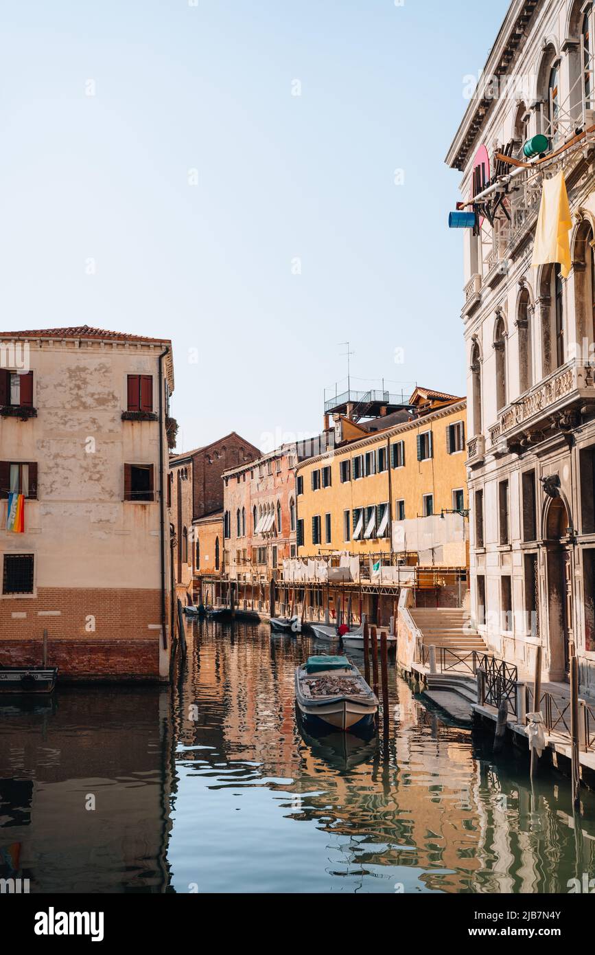 Venezia, Italia - 21 maggio 2022: Piccola barca di legno piena di rifiuti da costruzione ormeggiata su uno stretto canale di Venezia. Le barche sono la modalità principale di trasp Foto Stock