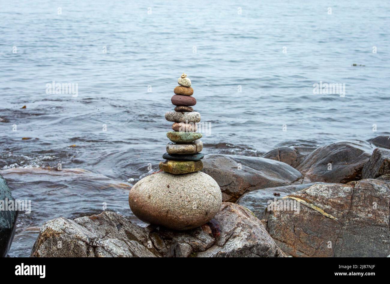 Stack di pietre vicino al mare con l'onda d'acqua sullo sfondo. Foto Stock