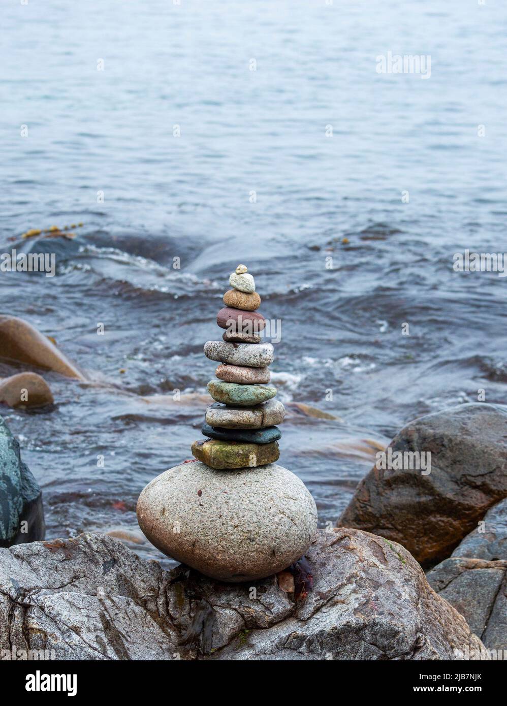 Stack di pietre vicino al mare con l'onda d'acqua sullo sfondo. Foto Stock