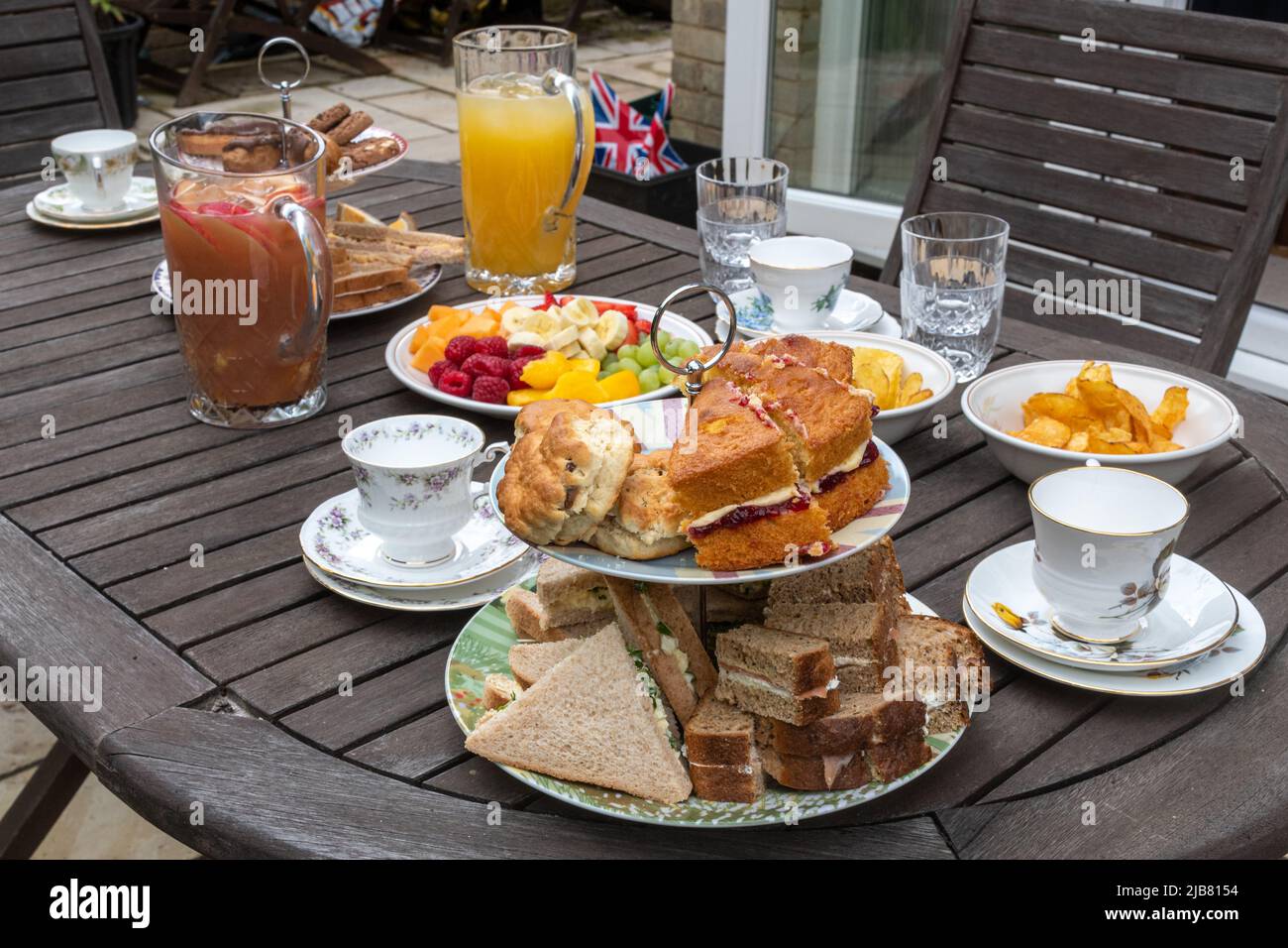 Il Giubileo della Regina's Platinum Bank Holiday - tavolo per un tè pomeridiano in famiglia in giardino con sandwich, torte, tè, succo di frutta e frutta, giugno 2022 Foto Stock