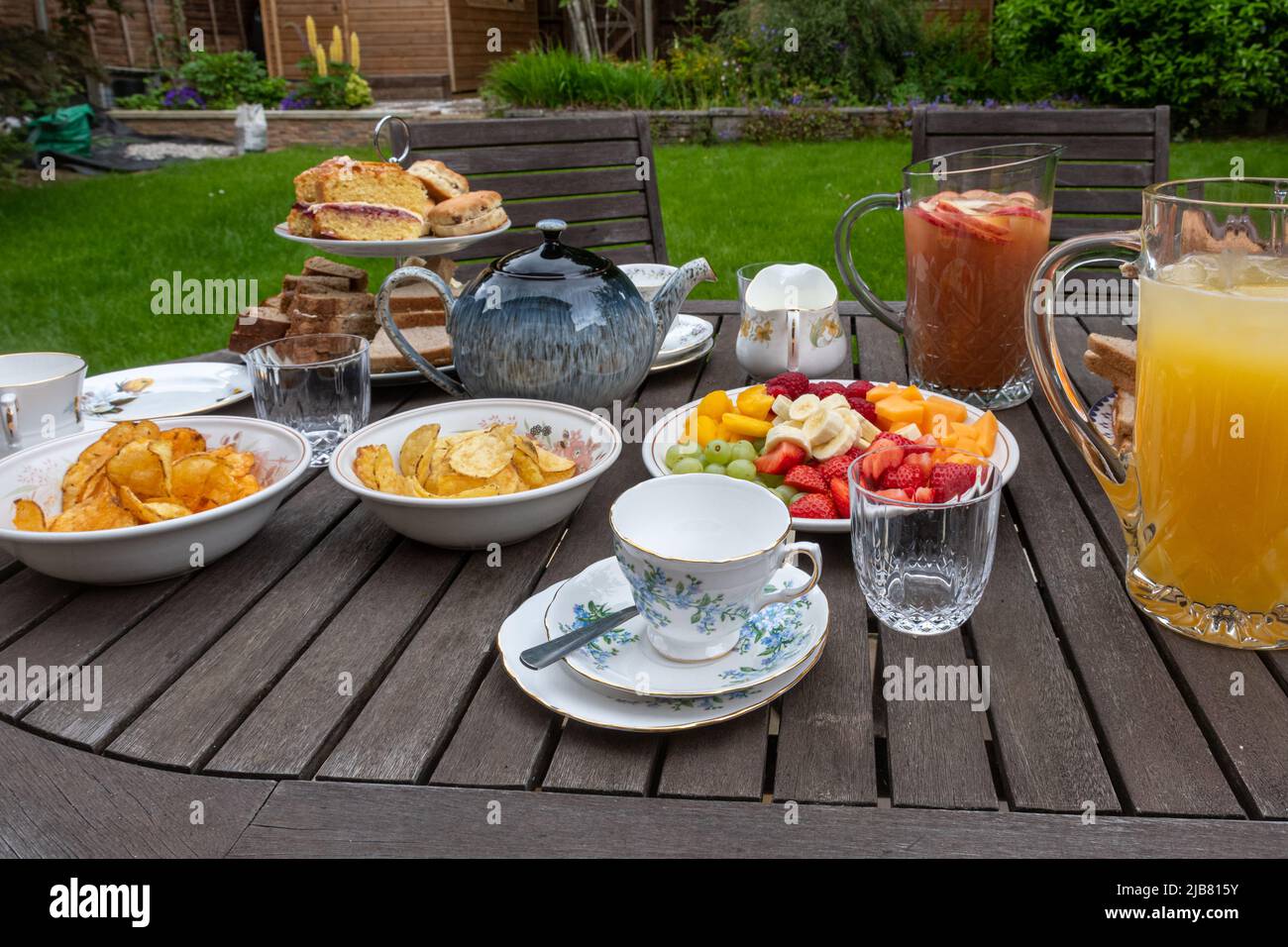 Il Giubileo della Regina's Platinum Bank Holiday - tavolo per un tè pomeridiano in famiglia in giardino con sandwich, torte, tè, succo di frutta e frutta, giugno 2022 Foto Stock