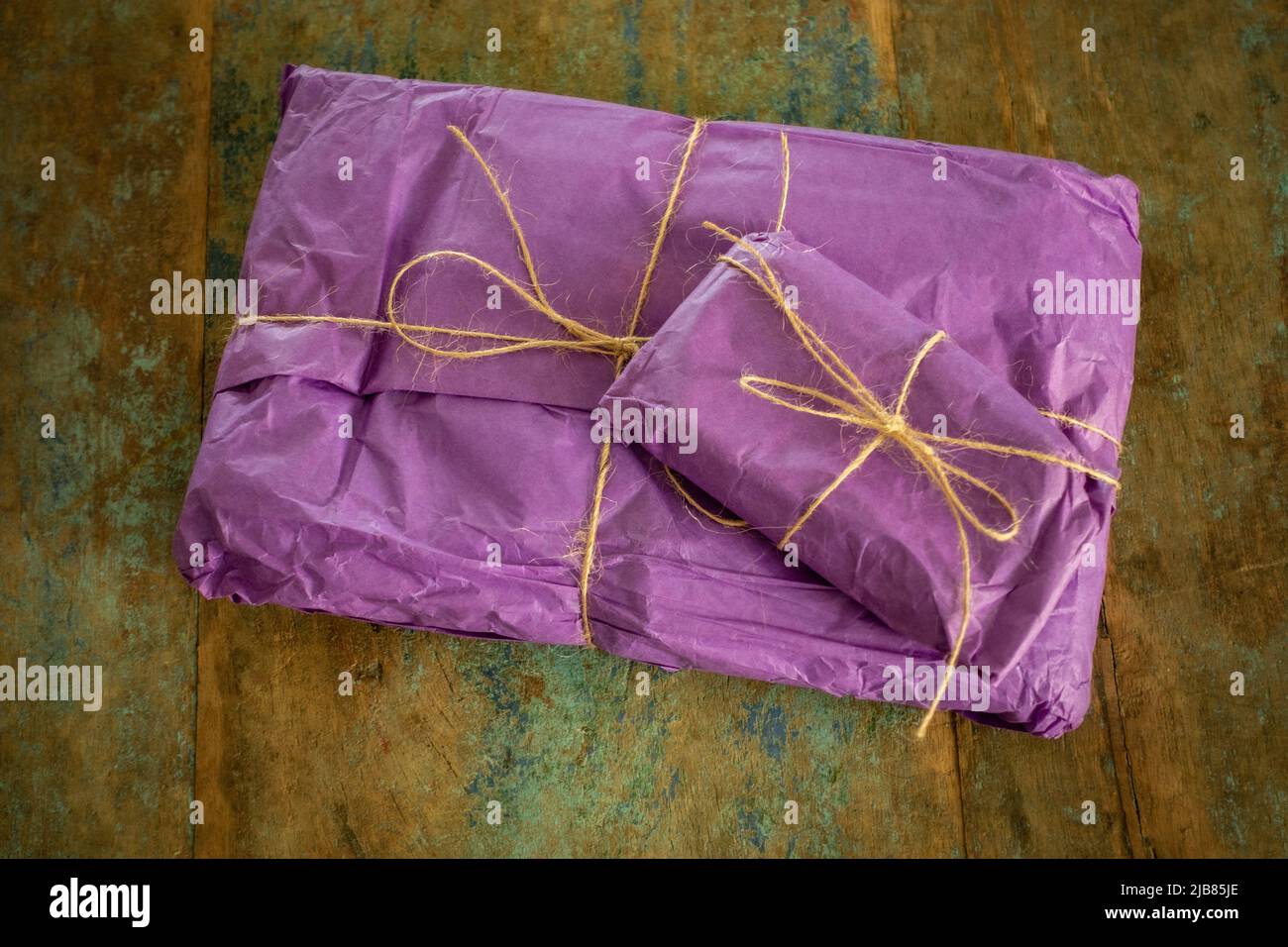 regalo confezionato in regalo, avvolto in tessuto viola e con arco a corda Foto Stock
