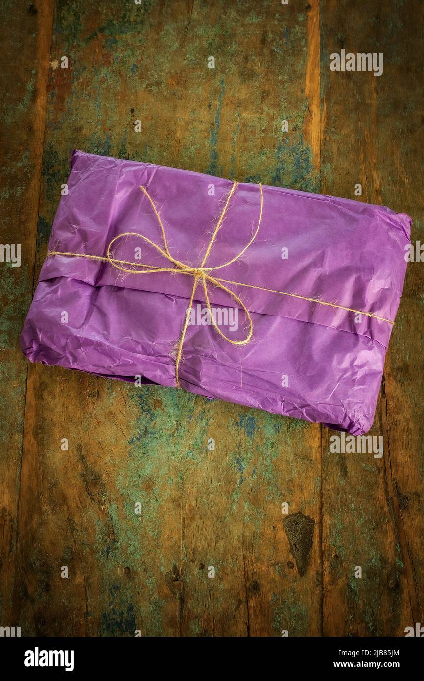 regalo confezionato in regalo, avvolto in tessuto viola e con arco a corda Foto Stock