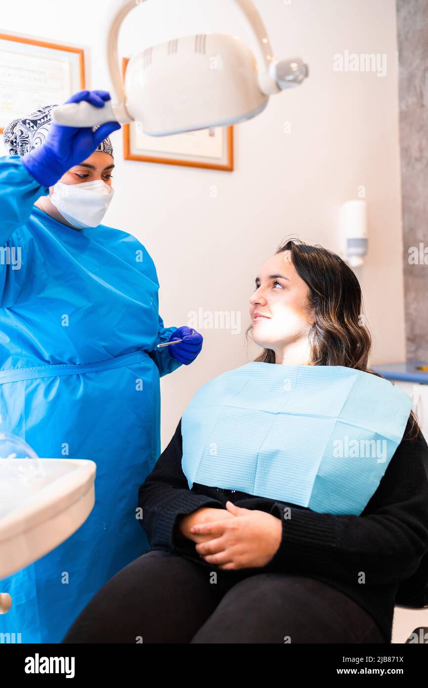 Dentista femminile che prepara la lampada per sedia dentale con una paziente femminile Foto Stock