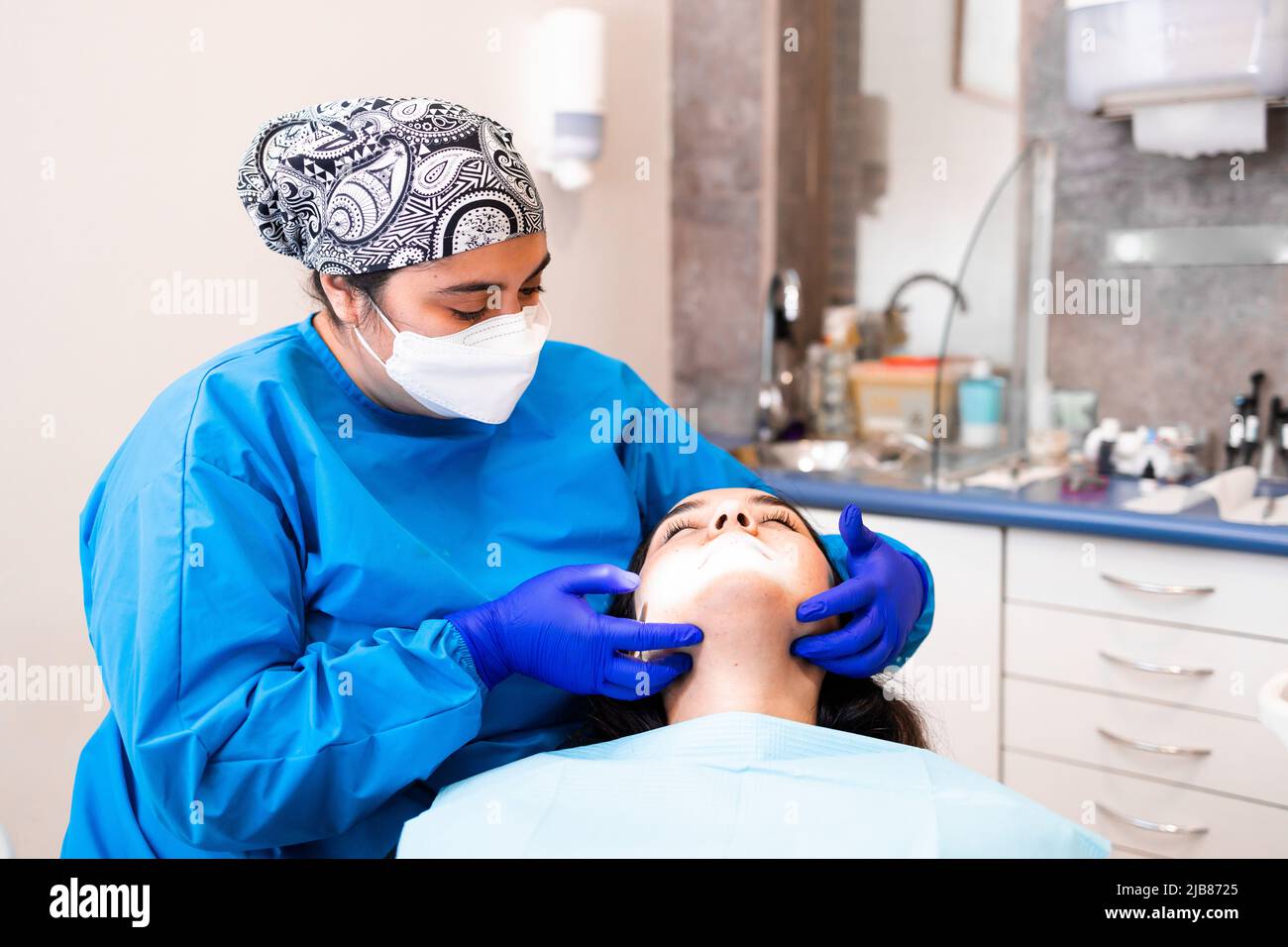 Dentista femminile palpando i linfonodi di un paziente Foto Stock