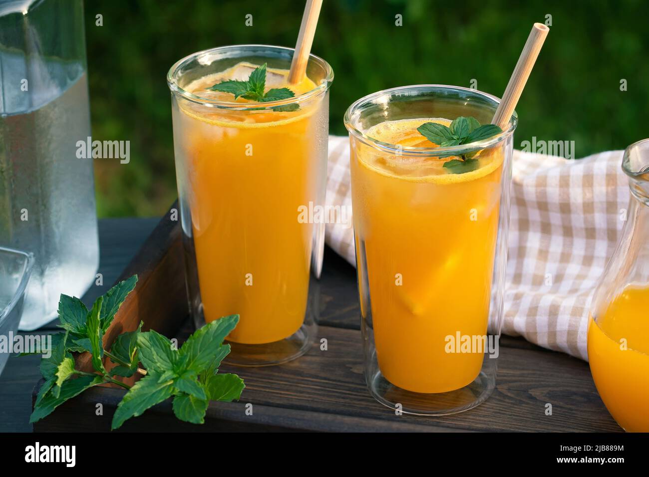 Rinfrescante cocktail estivo all'arancia fatto in casa in alti bicchieri doppi di vetro con menta e ghiaccio, focus selettivo Foto Stock