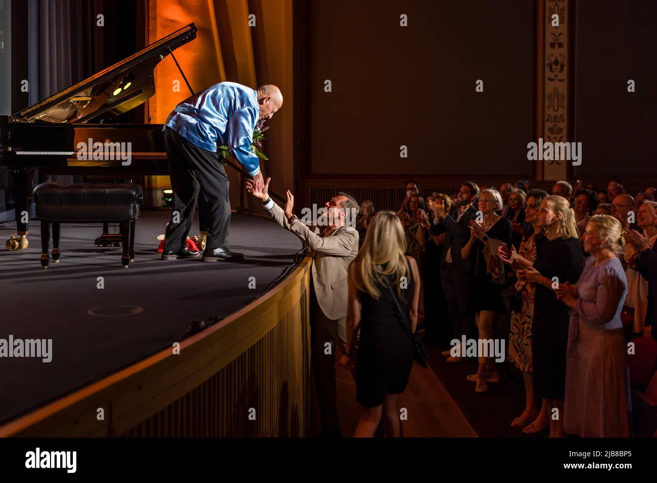 03 giugno 2022, Brandeburgo, Cottbus: Il sindaco di Cottbus Holger Kelch (2nd da sinistra) presenta fiori a David Helfgot (l) mentre i concertgoers applaudono. L'eccezionale pianista australiano David Helfgott ha tenuto un concerto nel cinema "Weltspiegel" di Cottbus. La città di Lusatia è una delle ultime tre sedi di concerti del pianista eccezionale fuori dalla sua Australia nativa, insieme a Lucerna e New York. David Helfgott è uno dei musicisti più famosi al mondo. Onorato di molti premi internazionali, nel 2006 è stato il primo musicista mai introdotto nella Walk of Fame in Australia. Pho Foto Stock