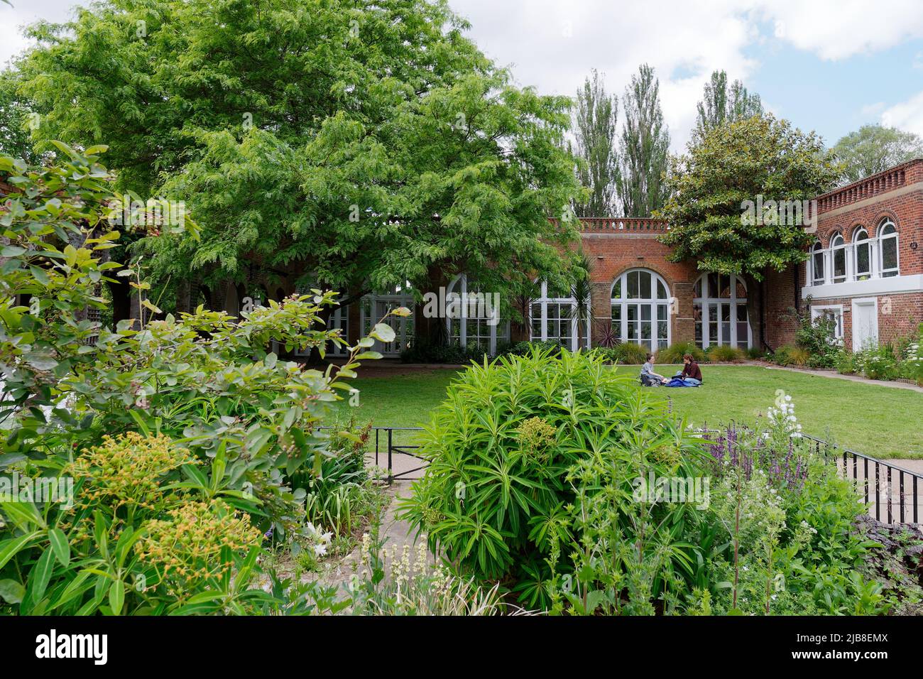 Londra, Greater London, Inghilterra, maggio 28 2022: La gente si siede e si rilassa sul prato accanto all'Orangery all'Holland Park nell'area di Kensington. Foto Stock