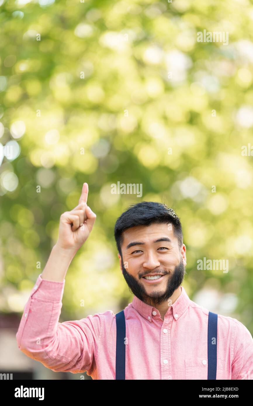 Uomo cinese in abiti casual che punta al cielo Foto Stock