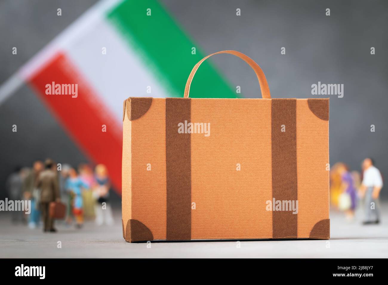 Valigia di cartone, giocattolo di plastica e una bandiera su uno sfondo astratto, un concetto sul tema di spostamento o di emigrazione dall'Iran Foto Stock