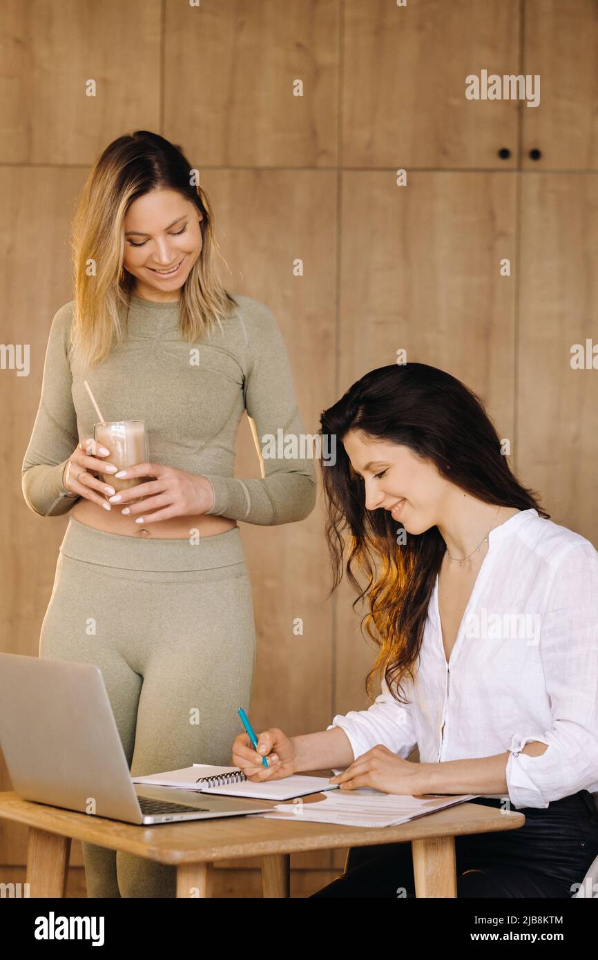 una ragazza dopo lezioni di fitness discute la sua dieta sana con un nutrizionista Foto Stock