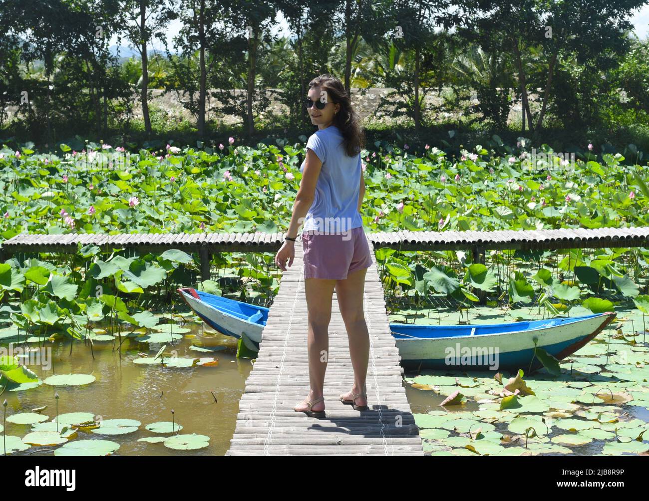 Giovane donna contro il lago di loto in Vietnam Foto Stock