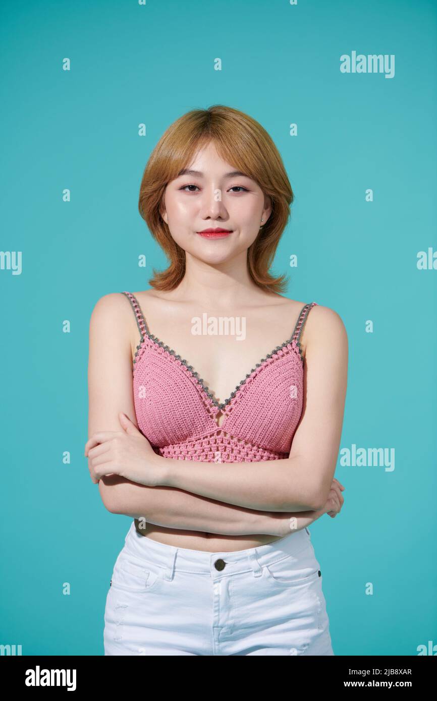 Ritratto di una bella giovane donna in abito estivo, mentre in piedi e ridendo isolato su sfondo turchese Foto Stock