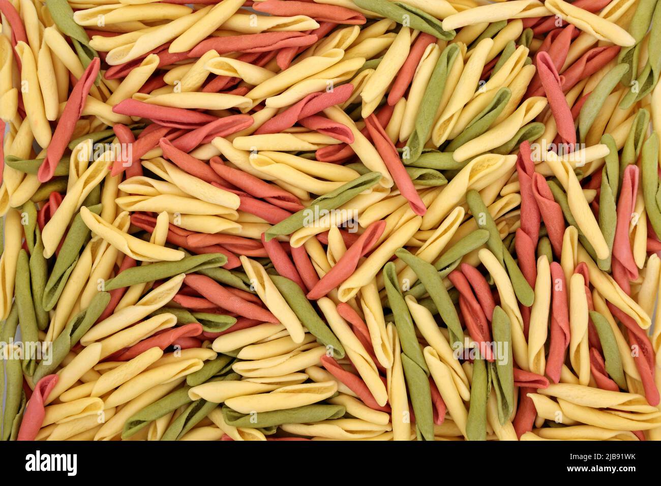 Fusilli pulgiesi pasta sana italiana formando un colorato sfondo astratto. Spinaci e pomodori alimenti verde e rosso colorazione a base di semola lingr Foto Stock