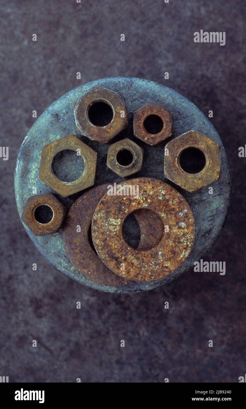 Usate dadi e rondelle in metallo arrugginito adagiati su metallo arginato Foto Stock