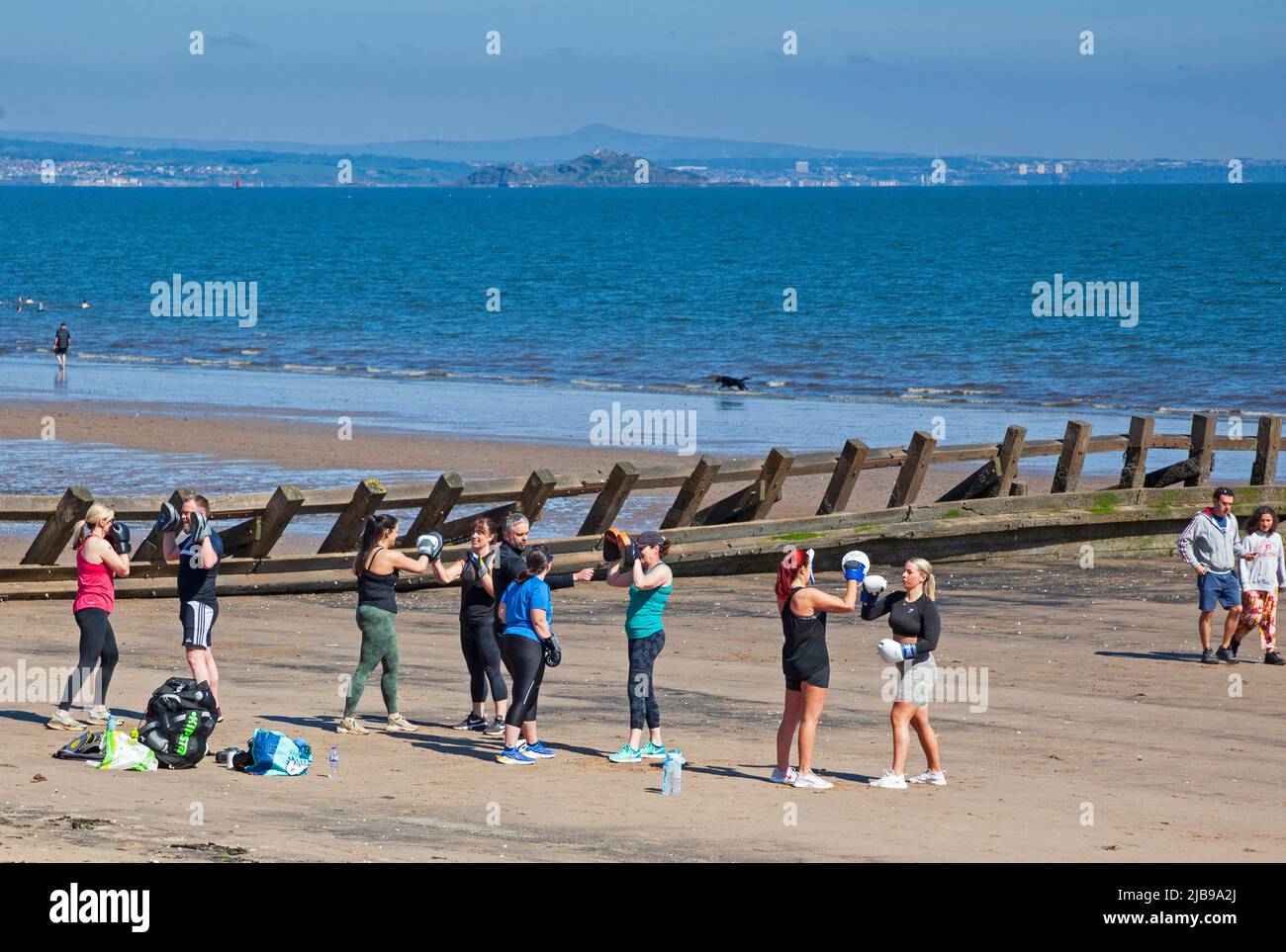 Portobello, Edimburgo, Scozia, Regno Unito. 4th giugno 2022, 13 gradi centigradi al mattino per il Platinum Jubilee Bank Holiday Sabato.Pictured: Esercizio di fitness boxe sulla spiaggia di sabbia con Firth of Forth in background. Credit: Scottisgriative/alamy Live News. Foto Stock