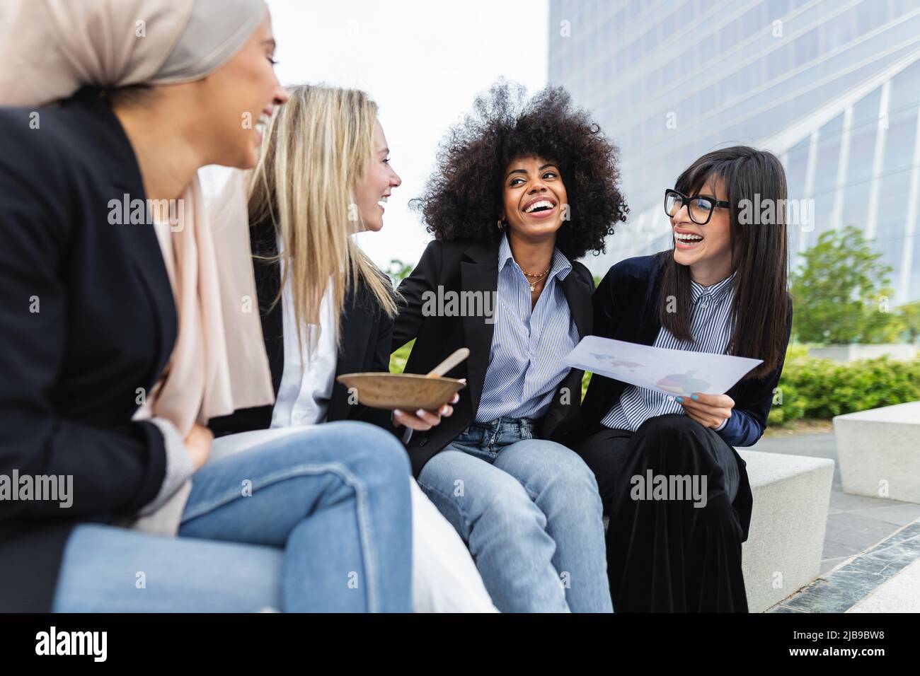 Donne multirazziali di affari che prendono una pausa mangiando un pasto fuori dell'ufficio Foto Stock