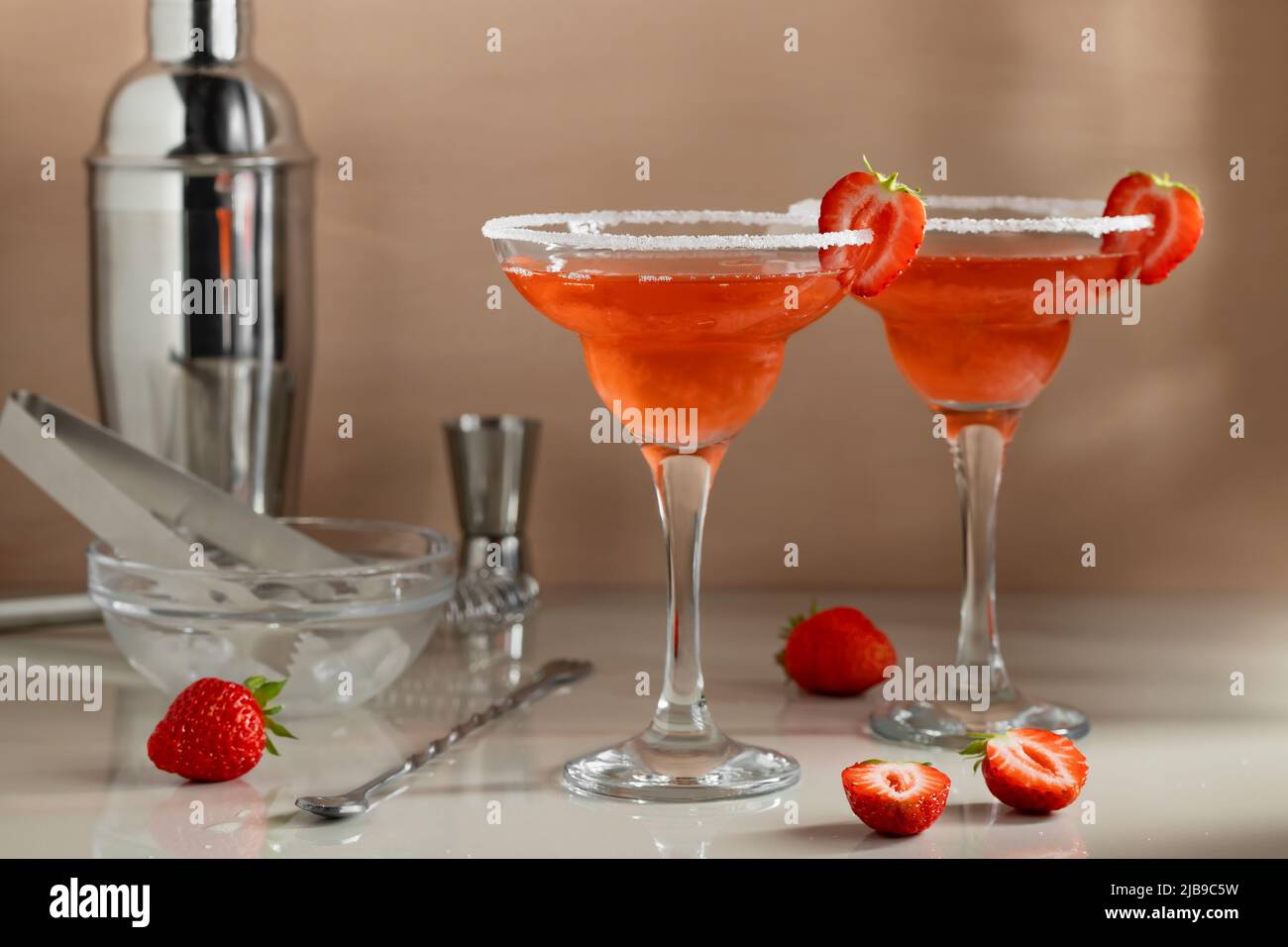 Cocktail margarita alla fragola fatti in casa con strumenti da bar sul tavolo. Preparazione di cocktail rinfrescanti estivi. Foto Stock