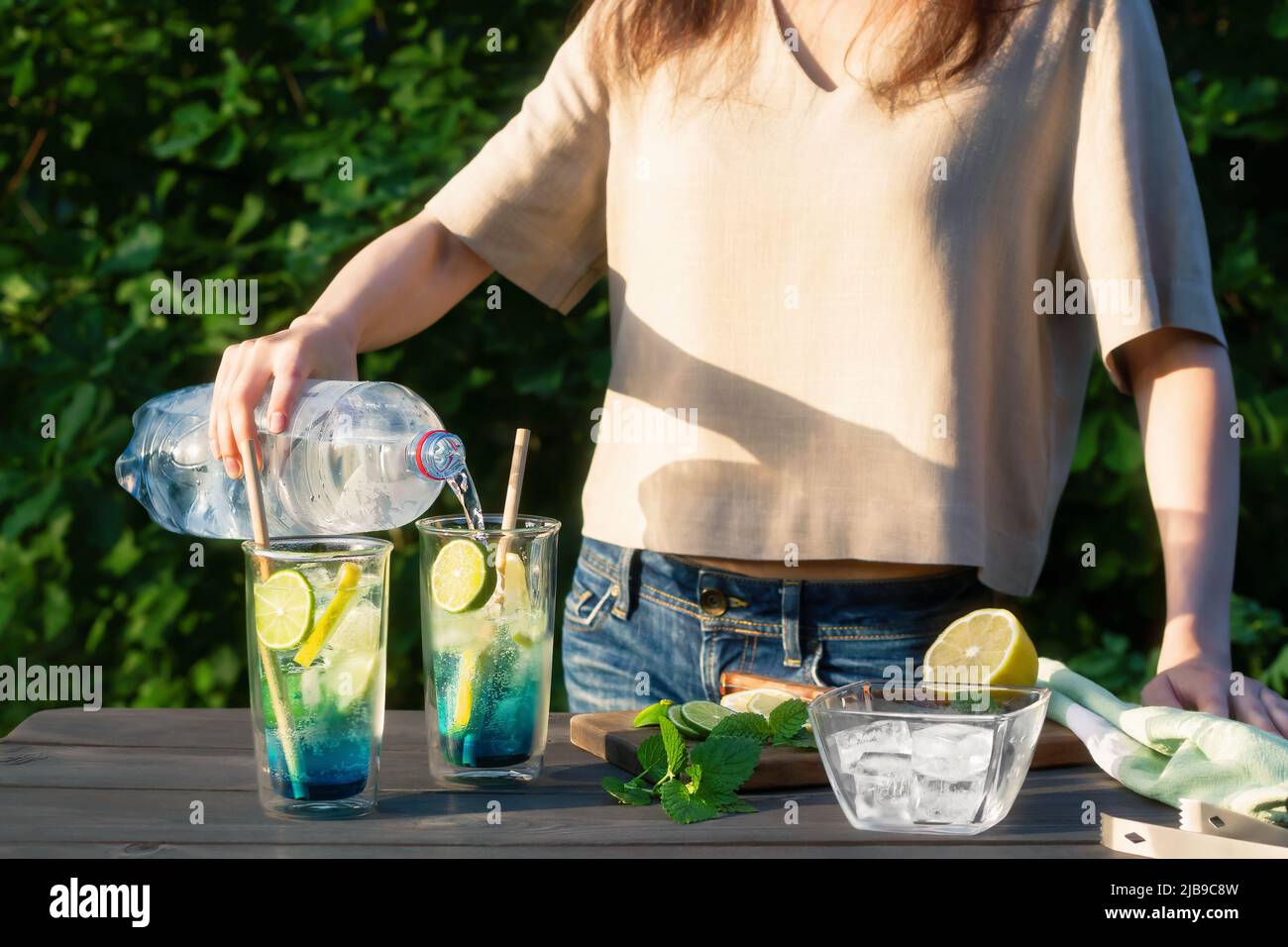 La ragazza fa i cocktail rinfrescanti estivi laguna blu. Processo di versare acqua in Occhies.Selective Focus. Foto Stock