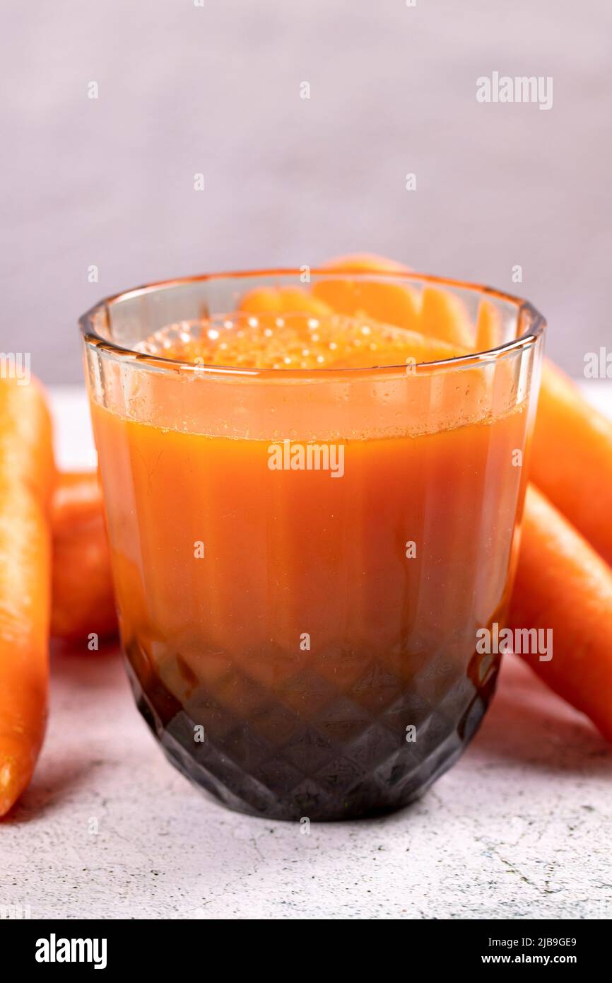 Succo di carota. Succo appena spremuto. Succo di carota appena spremuto in vetro su sfondo di pietra. Primo piano Foto Stock