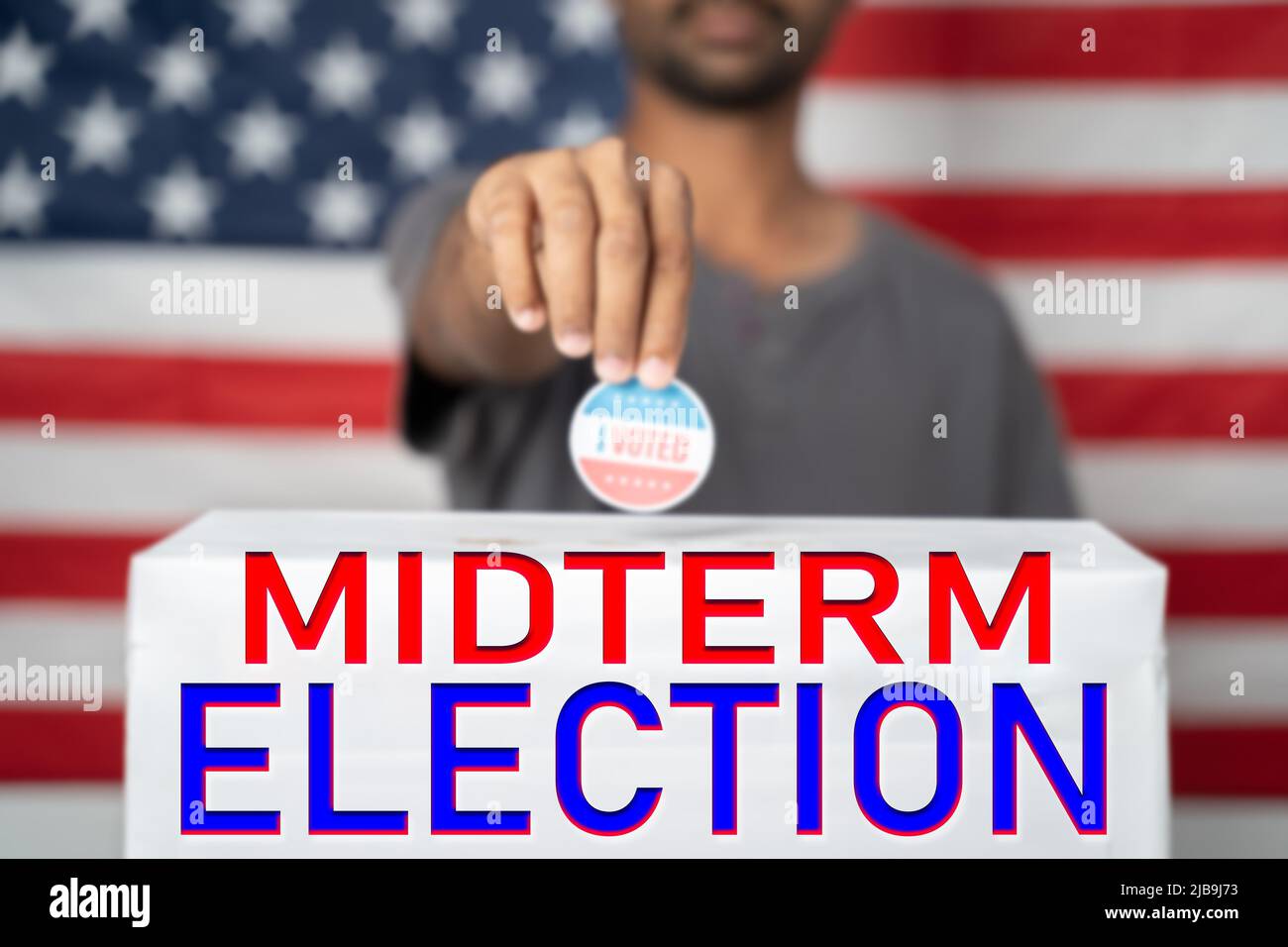 Il concetto di elezioni americane di Midterm del 2022 mostrando mettendo ho votato adesivo sulla scatola di voto con il segno di elezione di Midterm di fronte alla bandiera degli Stati Uniti Foto Stock