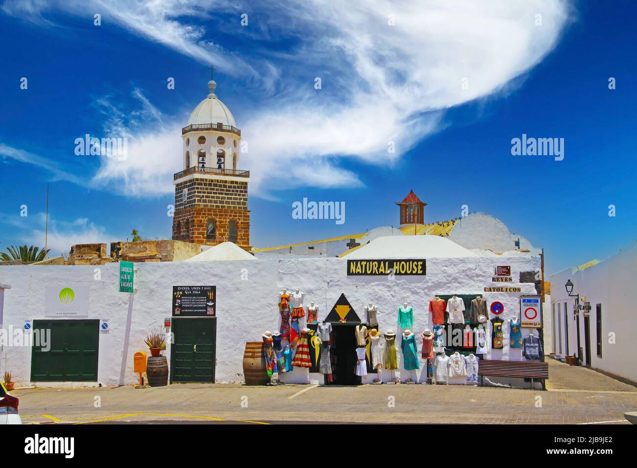 Teguise, Lanzarote - Juin 3. 2019: Bella città delle canarie bianca calma, negozio di abbigliamento tradizionale, piccolo vicolo stretto, torre della chiesa, cielo blu Foto Stock