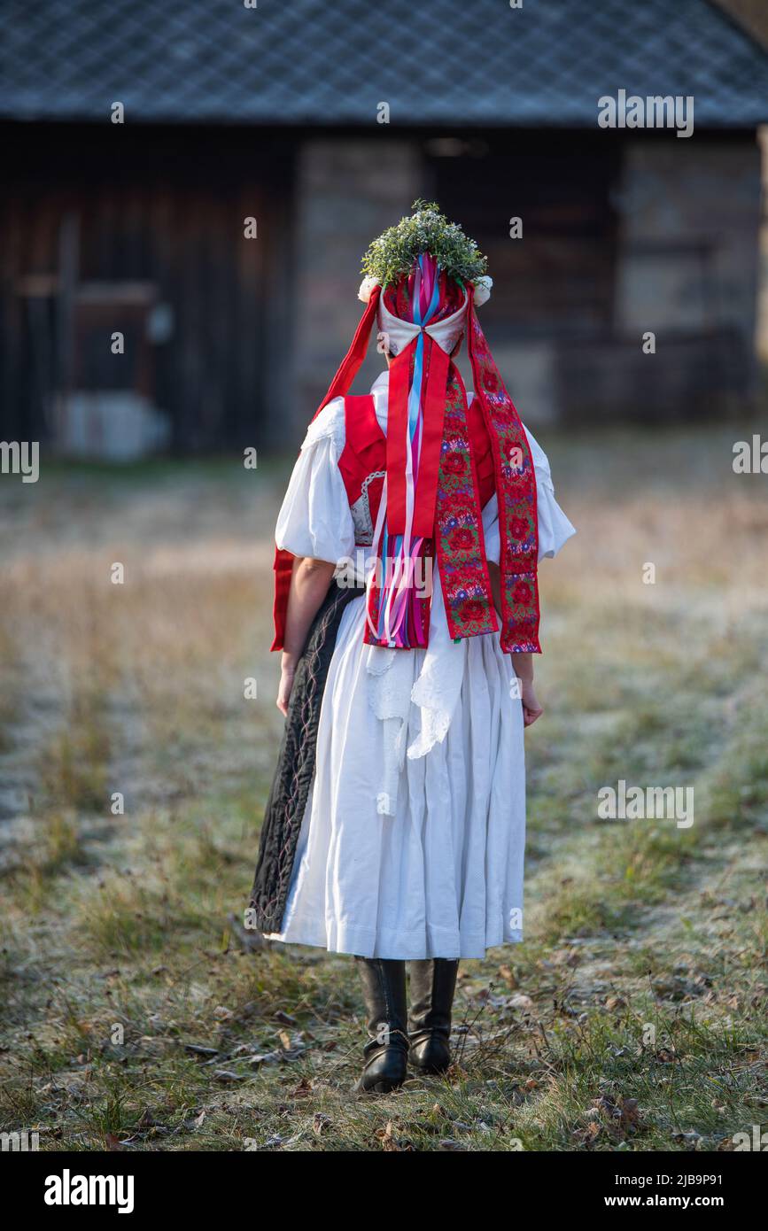 Donna vestita in costume tradizionale folk. Costume slovacco in autunno natura. Vecchio cottage di campagna sullo sfondo. Dettagli del costume slovacco di Detv Foto Stock