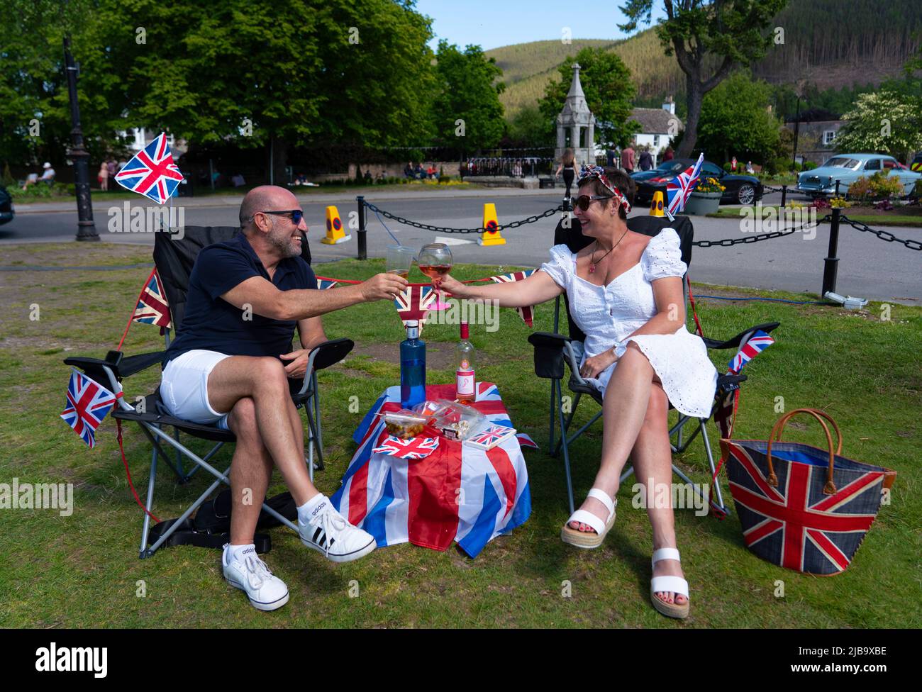 Ballater, Scozia, Regno Unito. 4 giugno 2022. La celebrazione del Giubileo del platino della Regina si celebra nel villaggio di Ballater, vicino a Balmoral, sul Royal Deeside, nell'Aberdeenshire. PIC; Julie e George dall'Hampshire godono di bevande sul prato nel verde del villaggio a Ballater. George era una guardia reale nella vicina Balmoral 40 anni fa. Iain Masterton/Alamy Live News Foto Stock