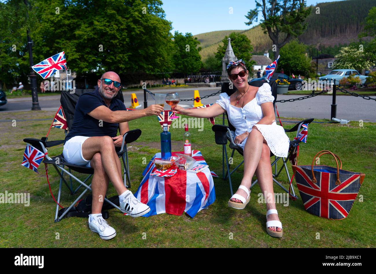 Ballater, Scozia, Regno Unito. 4 giugno 2022. La celebrazione del Giubileo del platino della Regina si celebra nel villaggio di Ballater, vicino a Balmoral, sul Royal Deeside, nell'Aberdeenshire. PIC; Julie e George dall'Hampshire godono di bevande sul prato nel verde del villaggio a Ballater. George era una guardia reale nella vicina Balmoral 40 anni fa. Iain Masterton/Alamy Live News Foto Stock