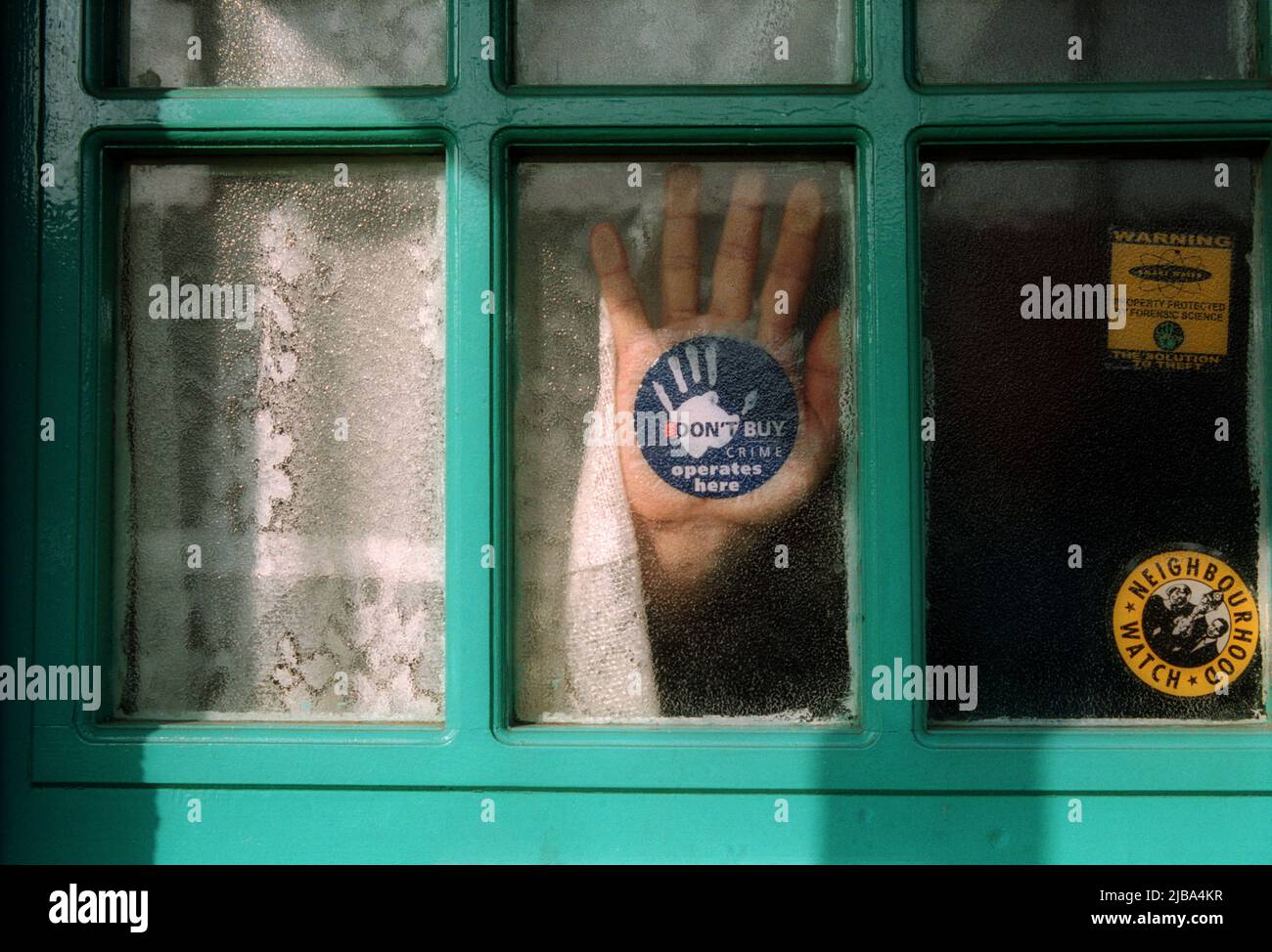 Adesivo Neighborhood Watch su una finestra con una mano contro la finestra Foto Stock